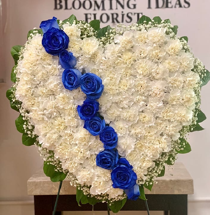Heart-shaped white floral arrangement with a diagonal line of blue roses