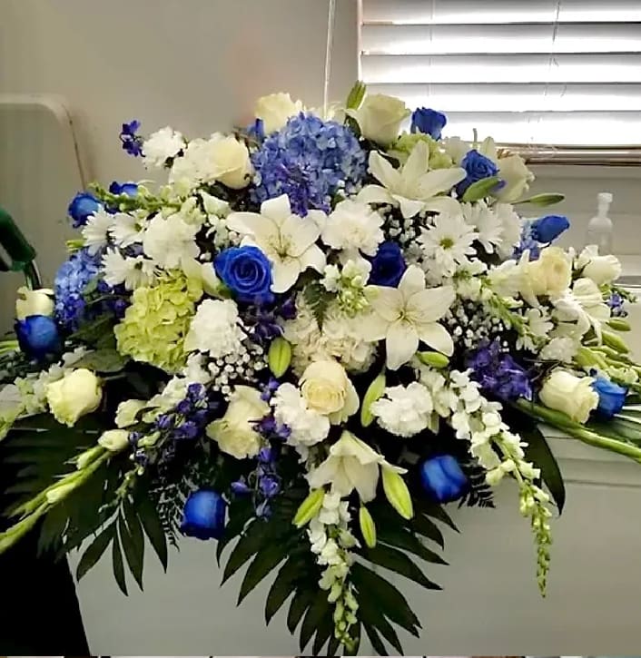 Large blue and white floral arrangement with lilies, roses, and hydrangeas