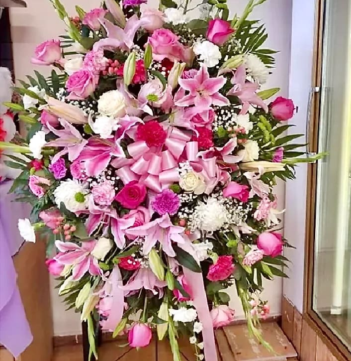 Large pink and white floral standing arrangement with a ribbon bow