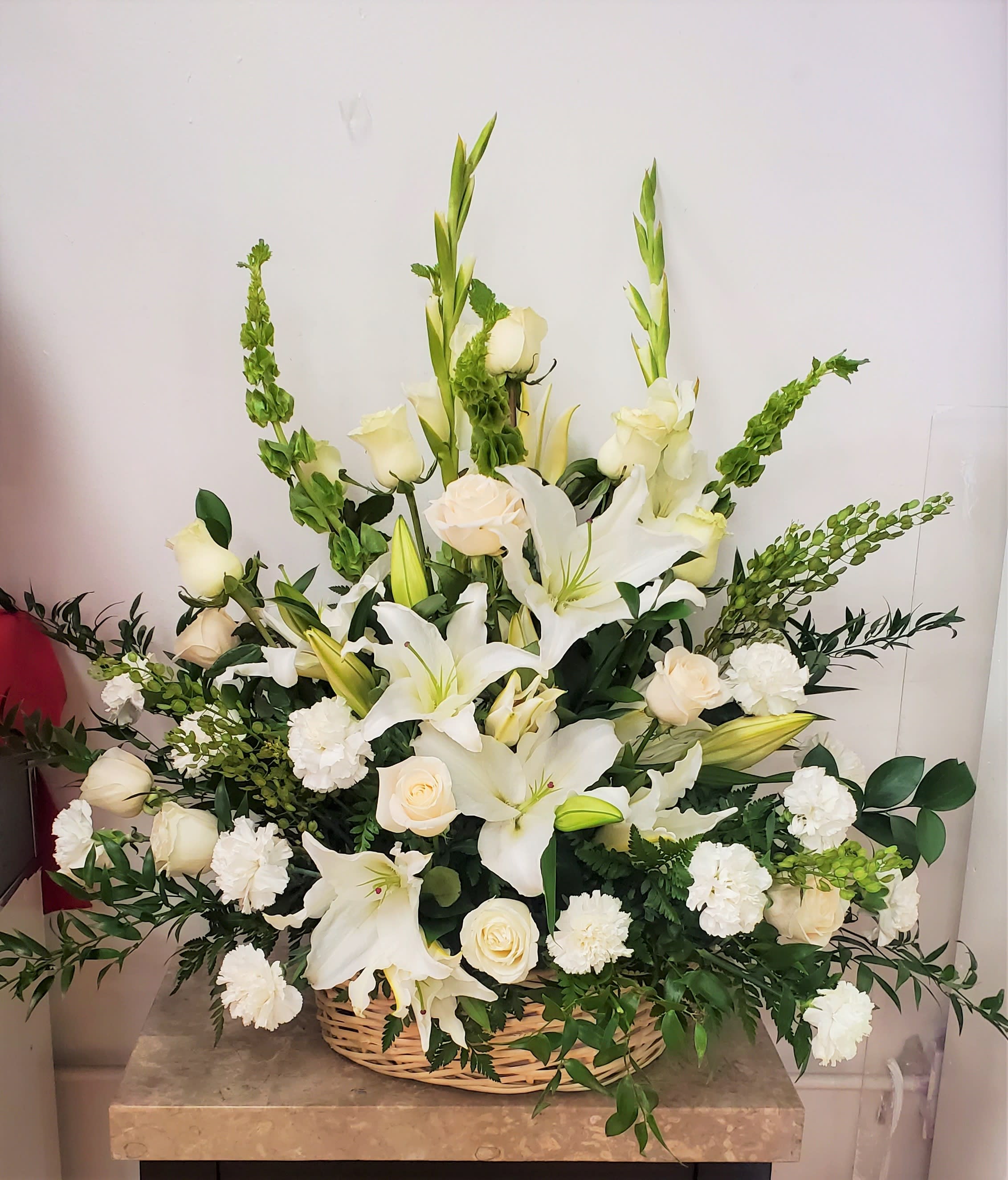 White lilies and roses arranged in a wicker basket