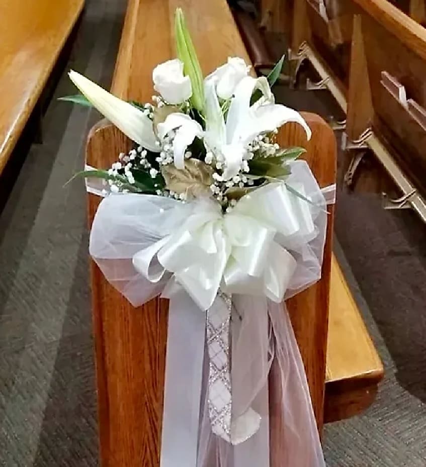 White lily bouquet with a large satin bow on a church pew