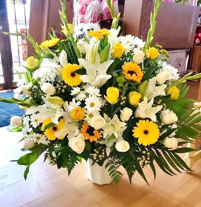 Large white and yellow floral arrangement in a white vase