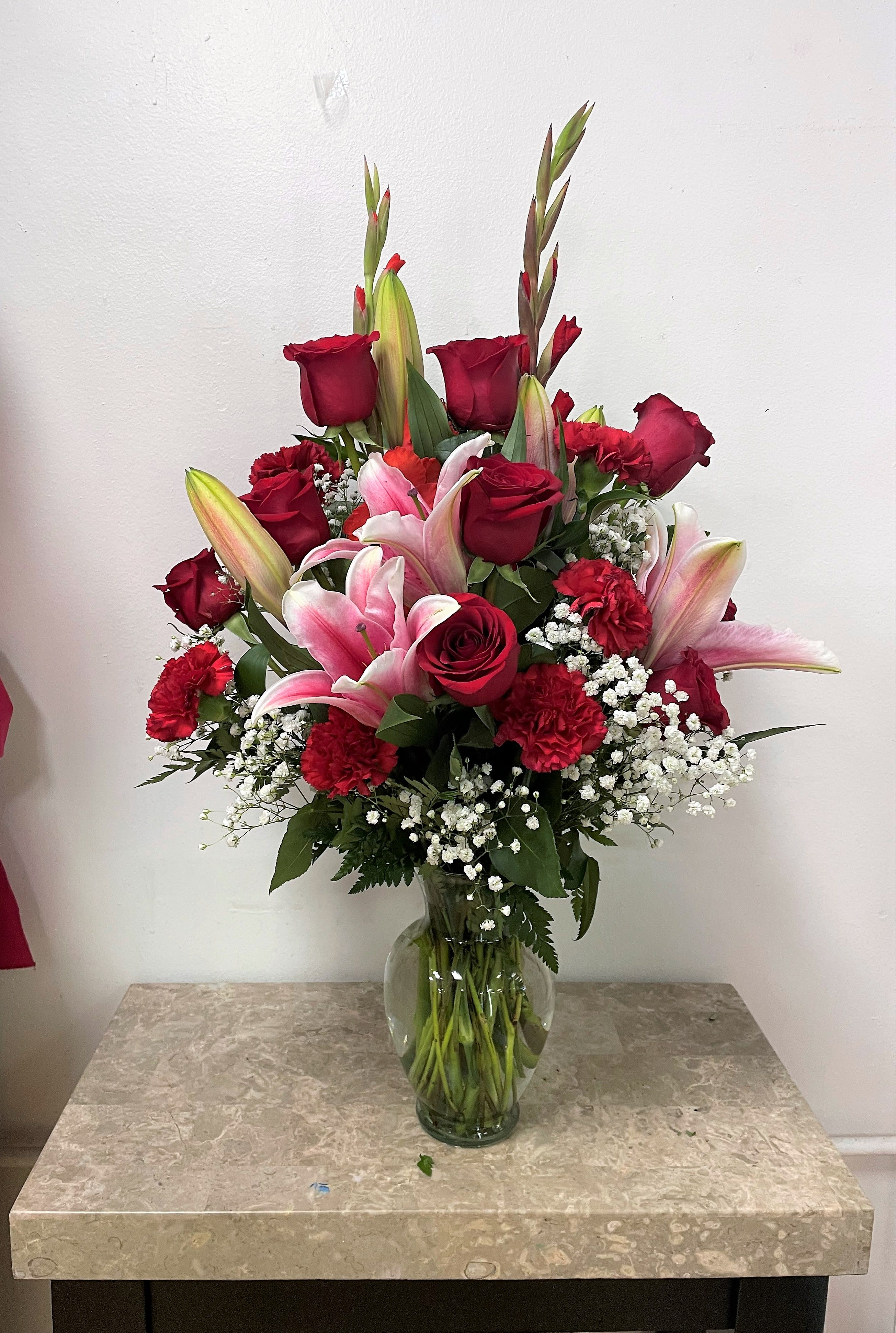 Red roses and pink lilies in a clear glass vase