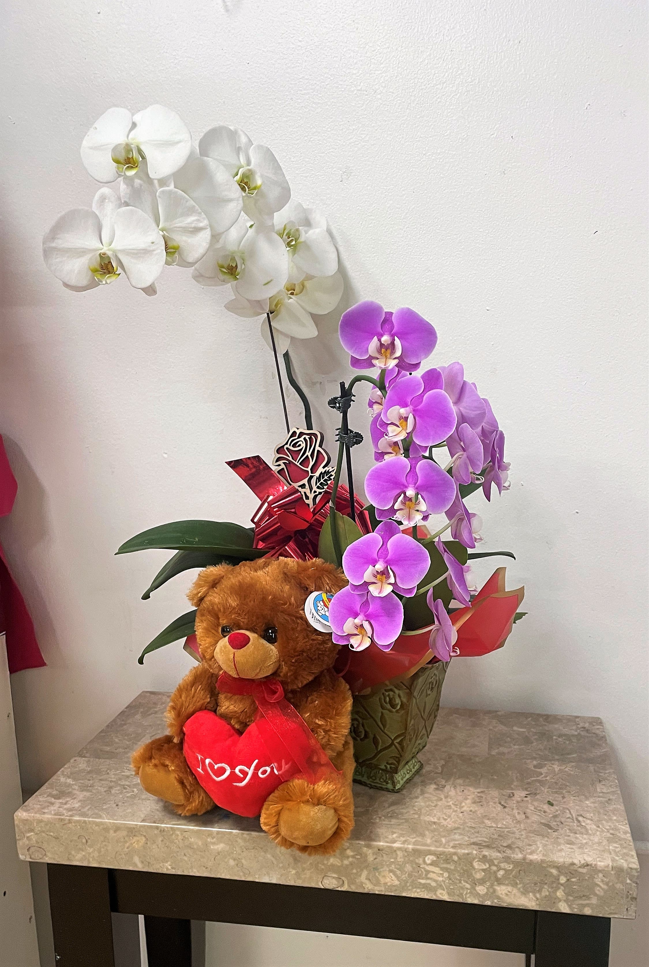 Potted orchids with a teddy bear holding a red heart