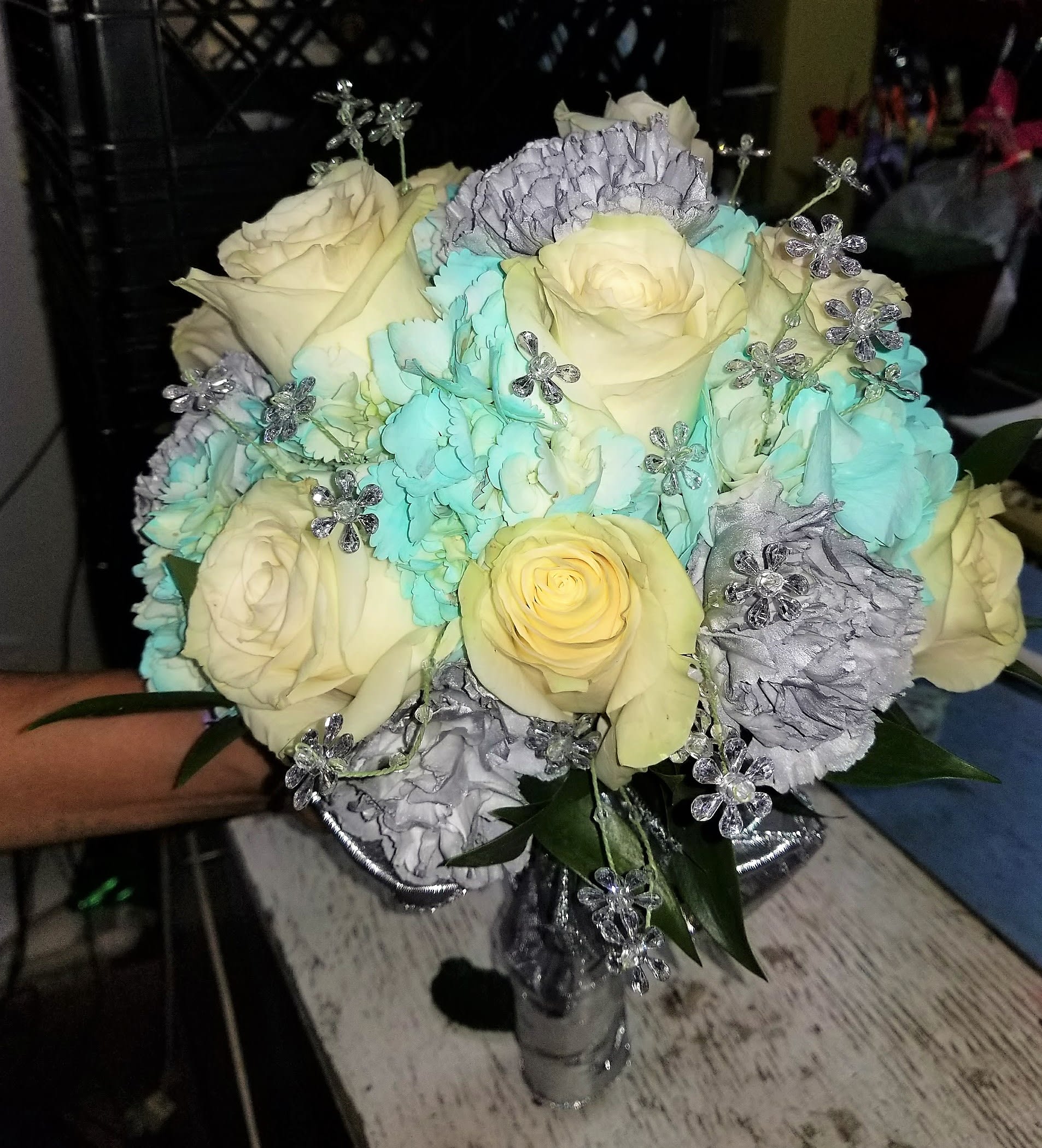 Bouquet of cream roses, blue carnations, and silver floral accents