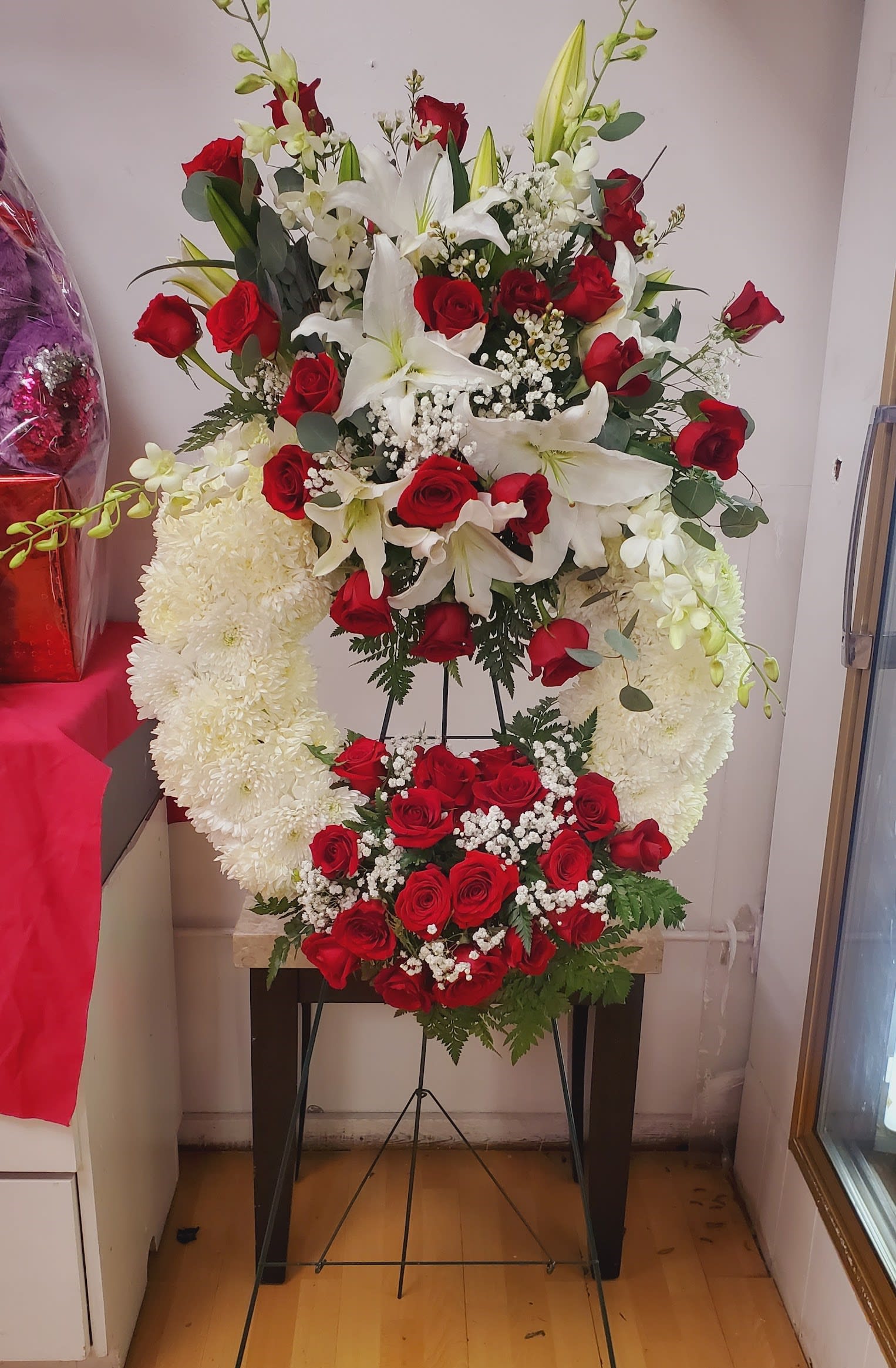 Standing floral tribute with red roses, white lilies, and white chrysanthemums