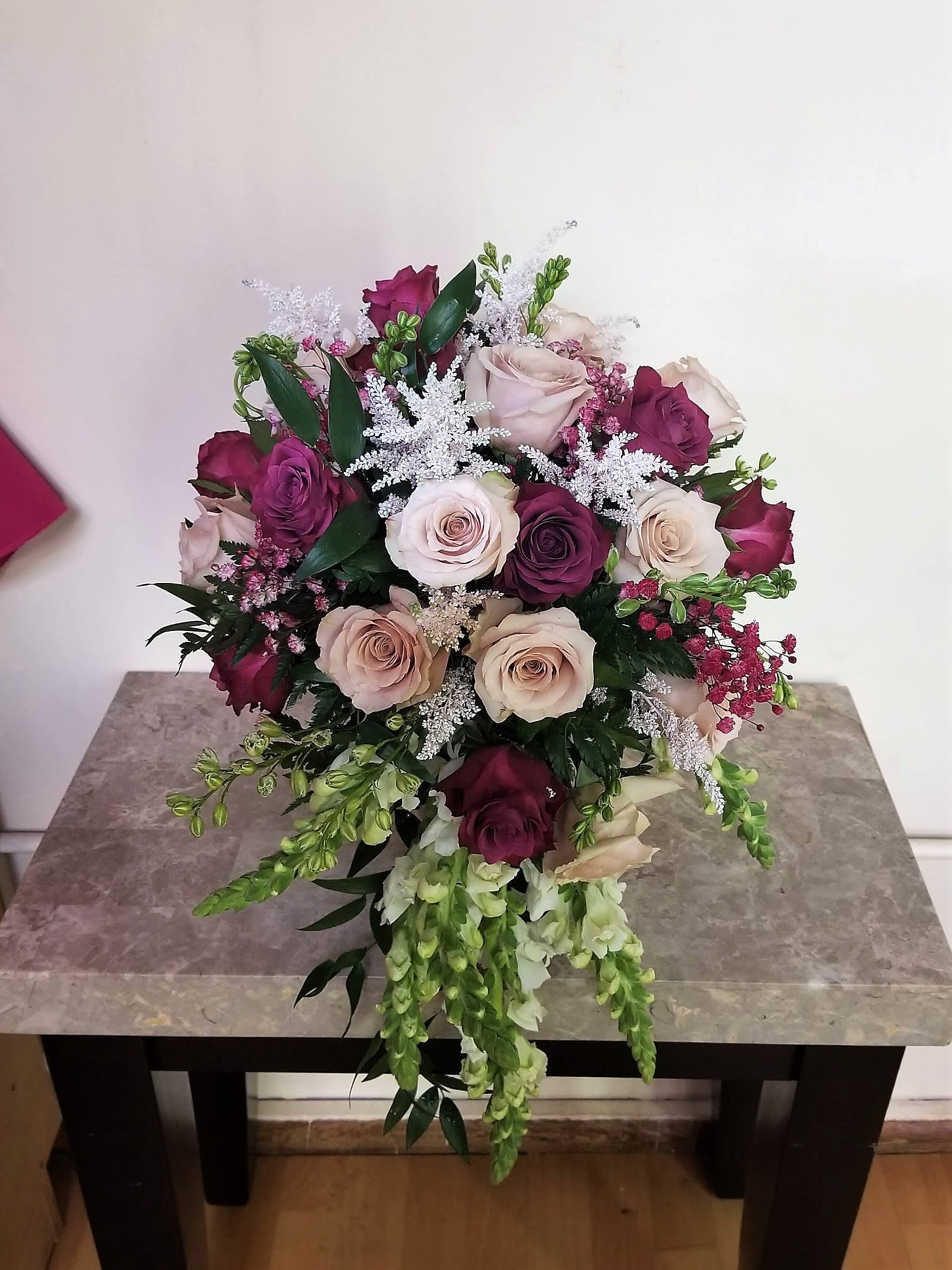 Bouquet of pink, cream, and burgundy roses with trailing white flowers