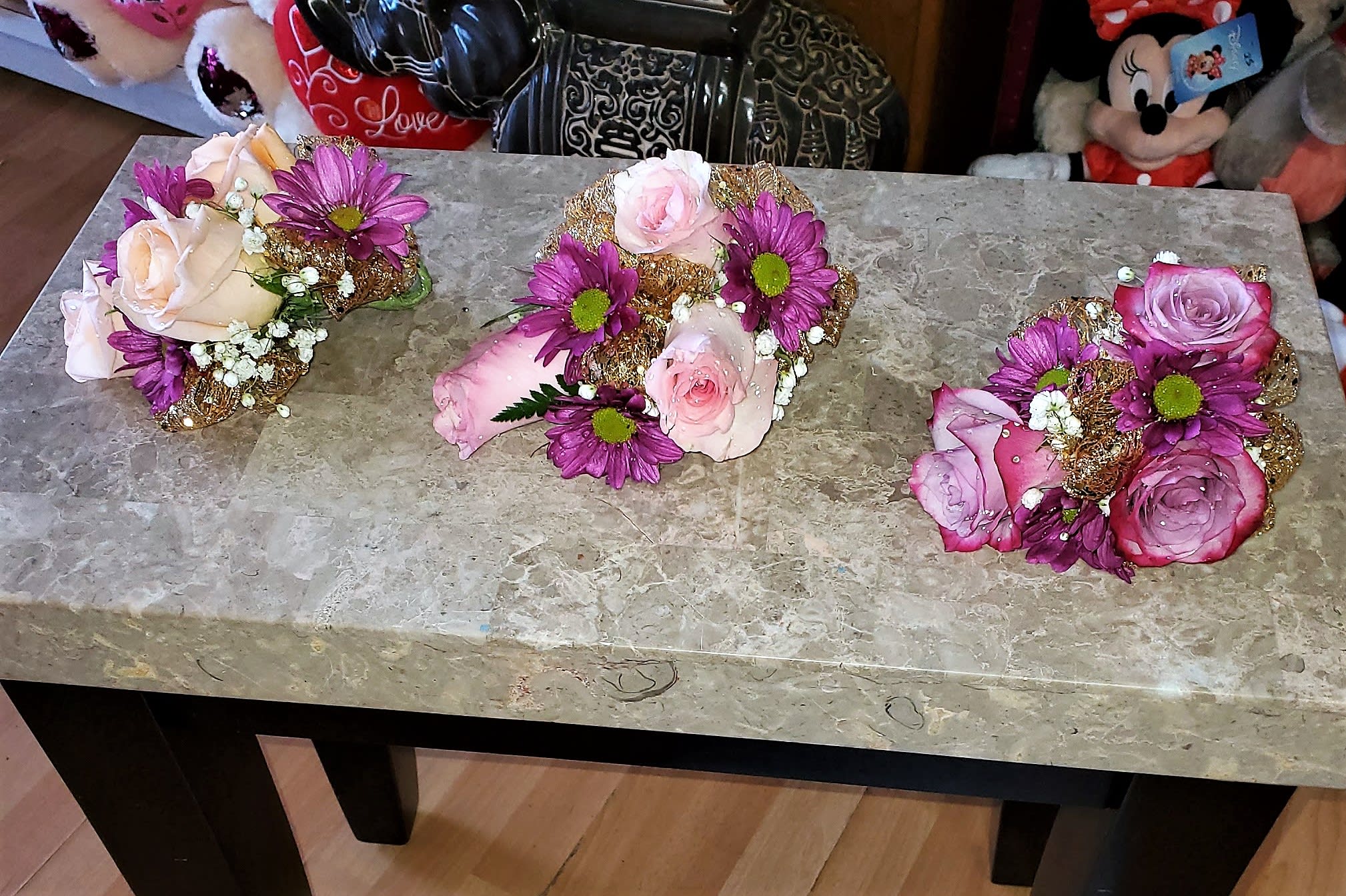 Three small rose and daisy floral arrangements on a table