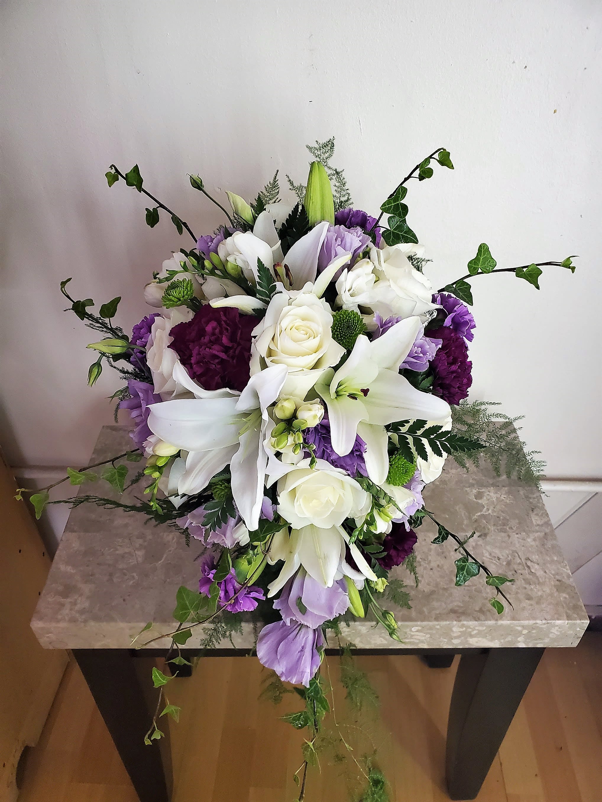 White lilies and roses with purple flowers in a low arrangement