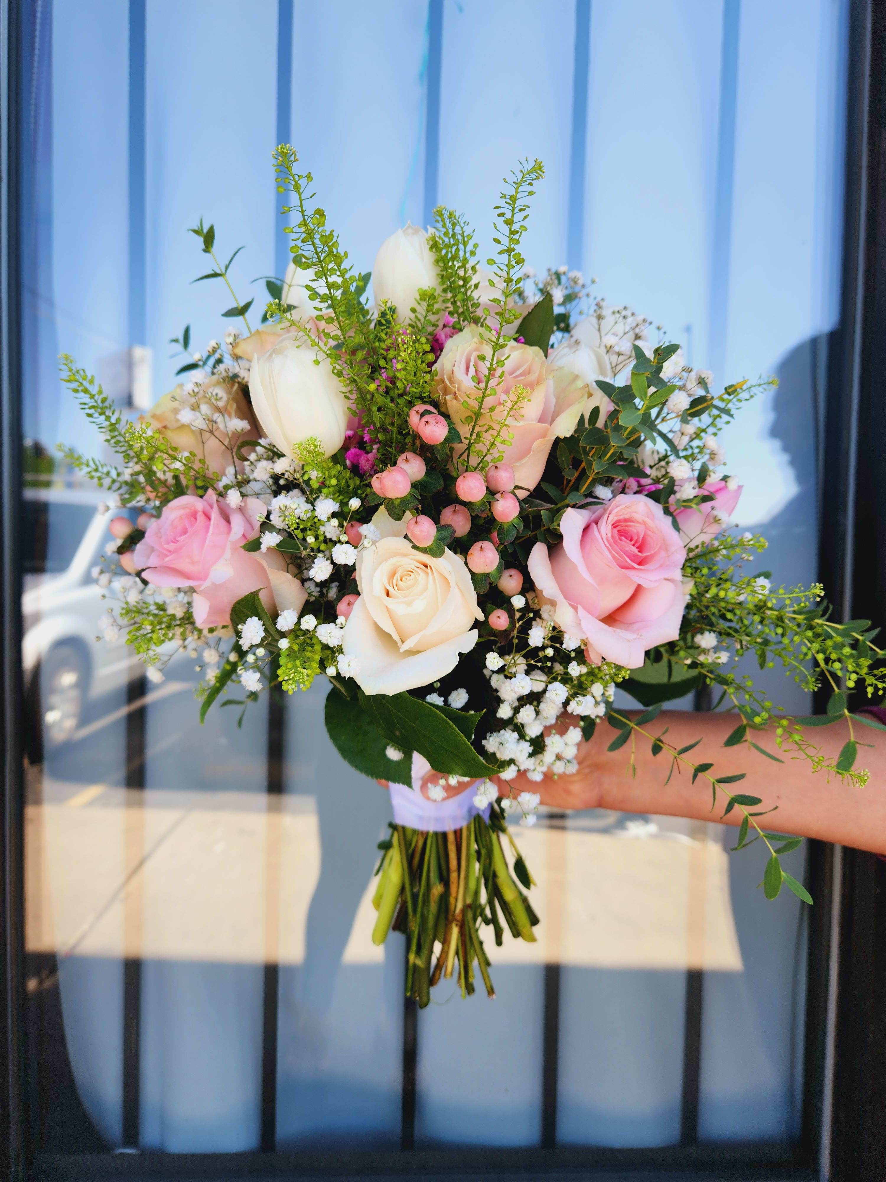 Handheld bouquet of pink and white roses with small white filler flowers