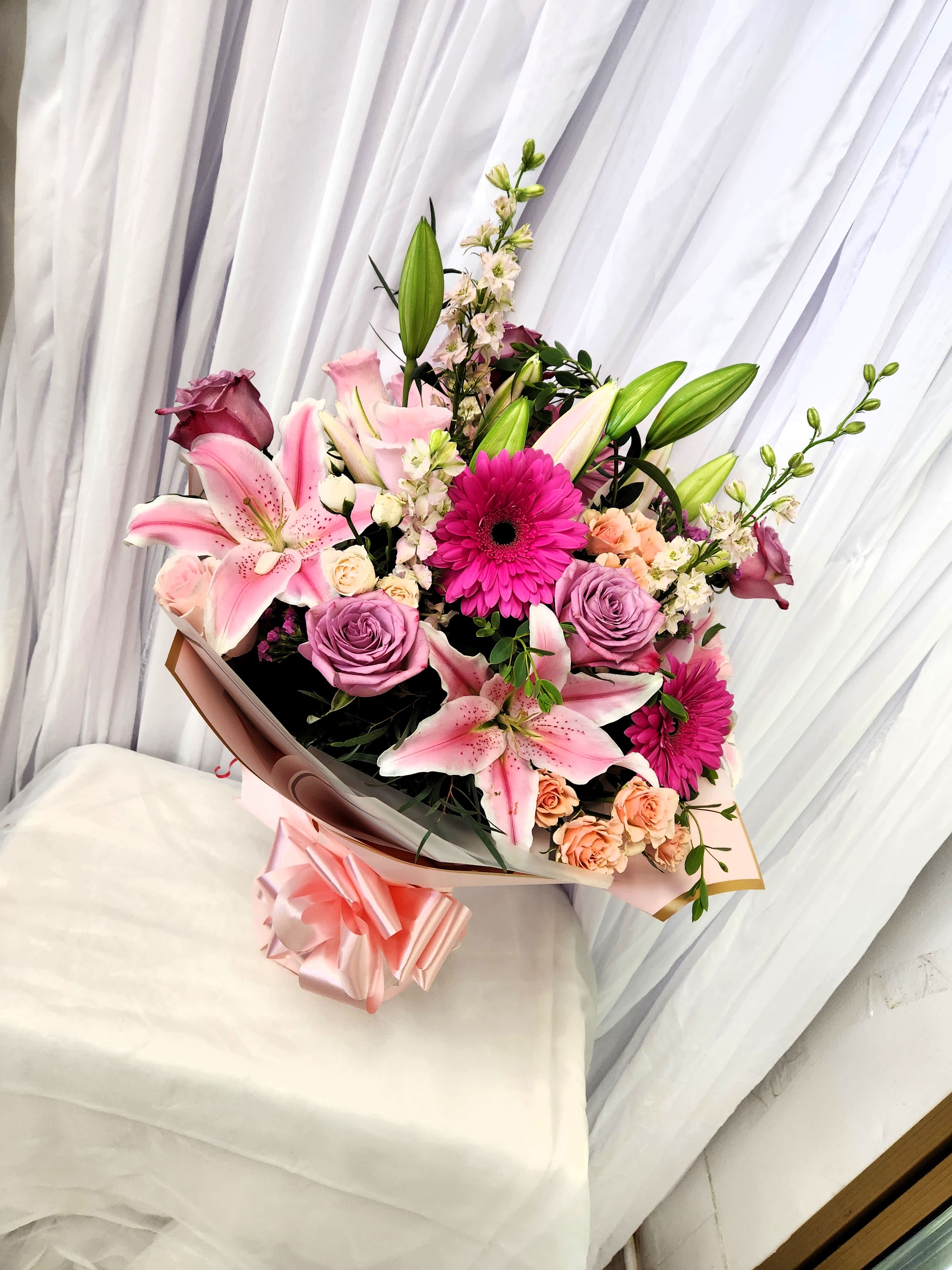 Bouquet of pink lilies, purple roses, and magenta gerbera daisies