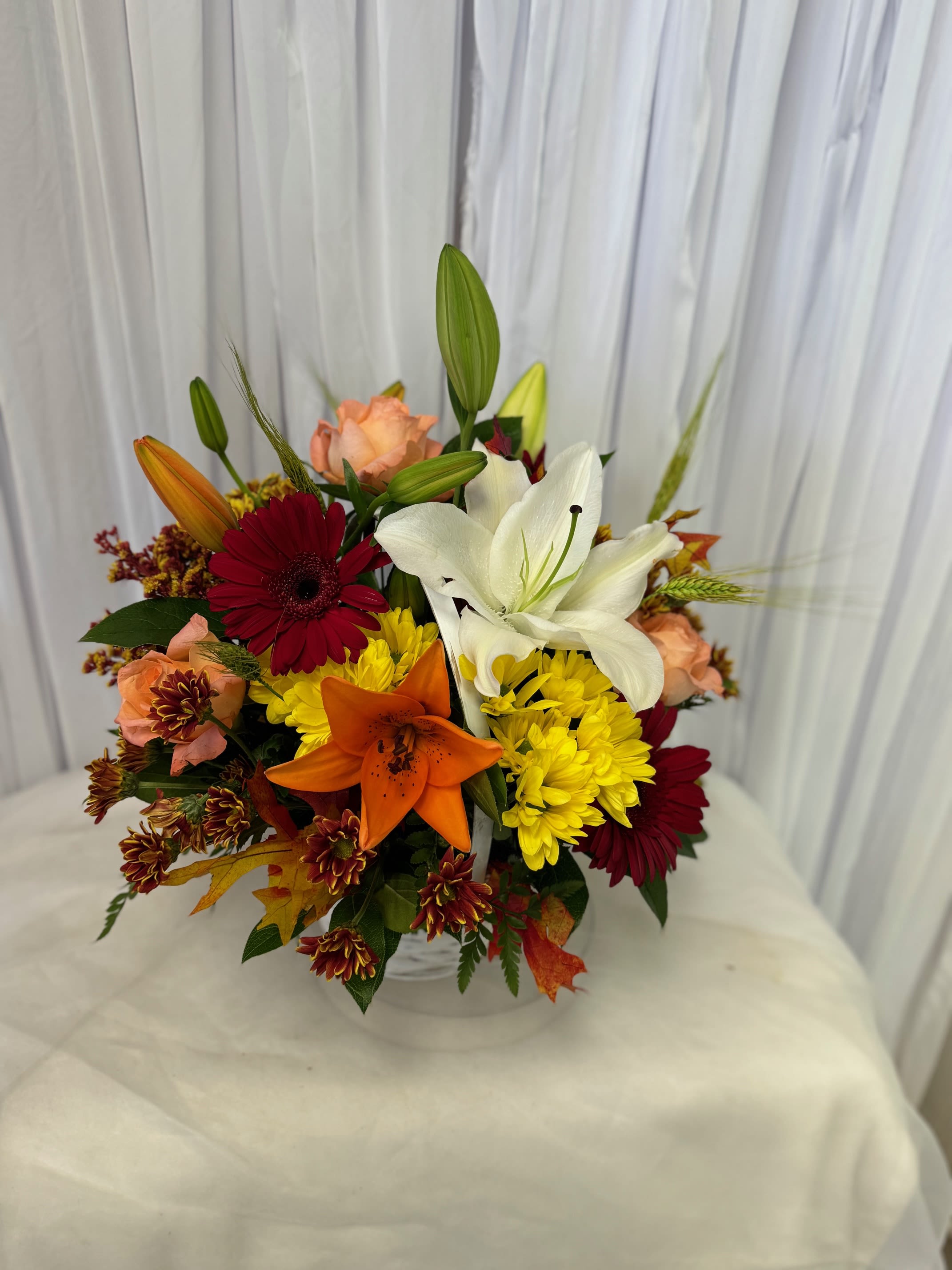 Mixed bouquet with lilies, gerbera daisies, and chrysanthemums in a clear vase