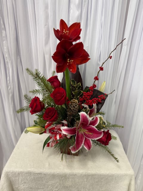Red amaryllis and roses arranged with lilies in a vase