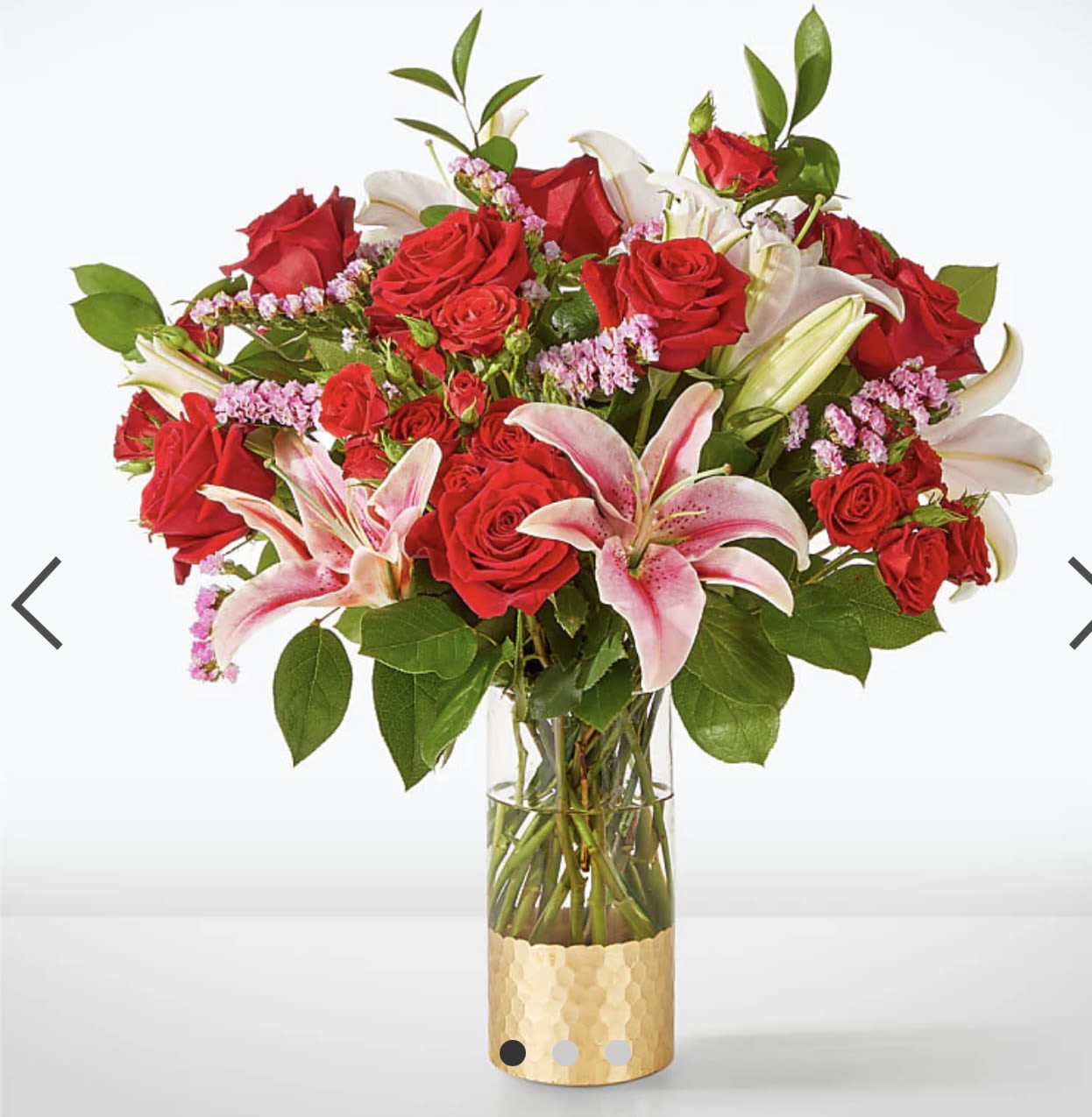 Bouquet of red roses and pink lilies in a clear glass vase
