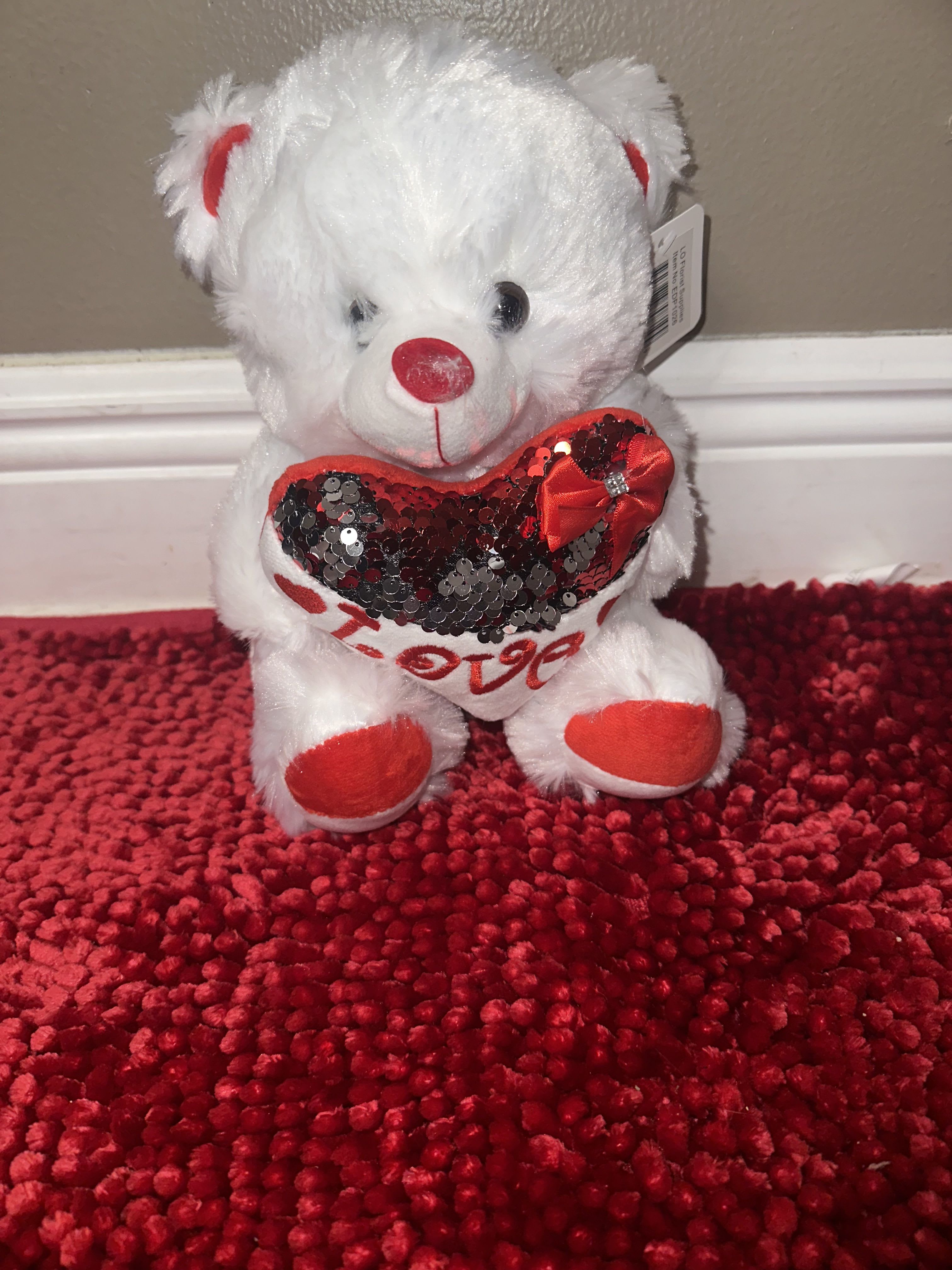 White plush teddy bear holding a red sequined heart