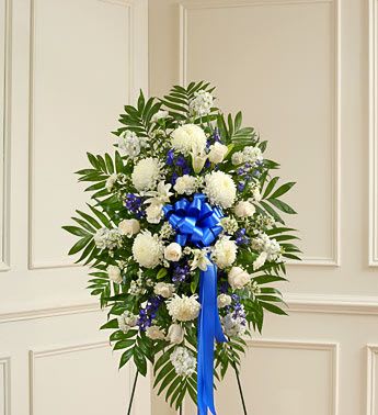 Standing floral spray of white and blue flowers with a blue ribbon