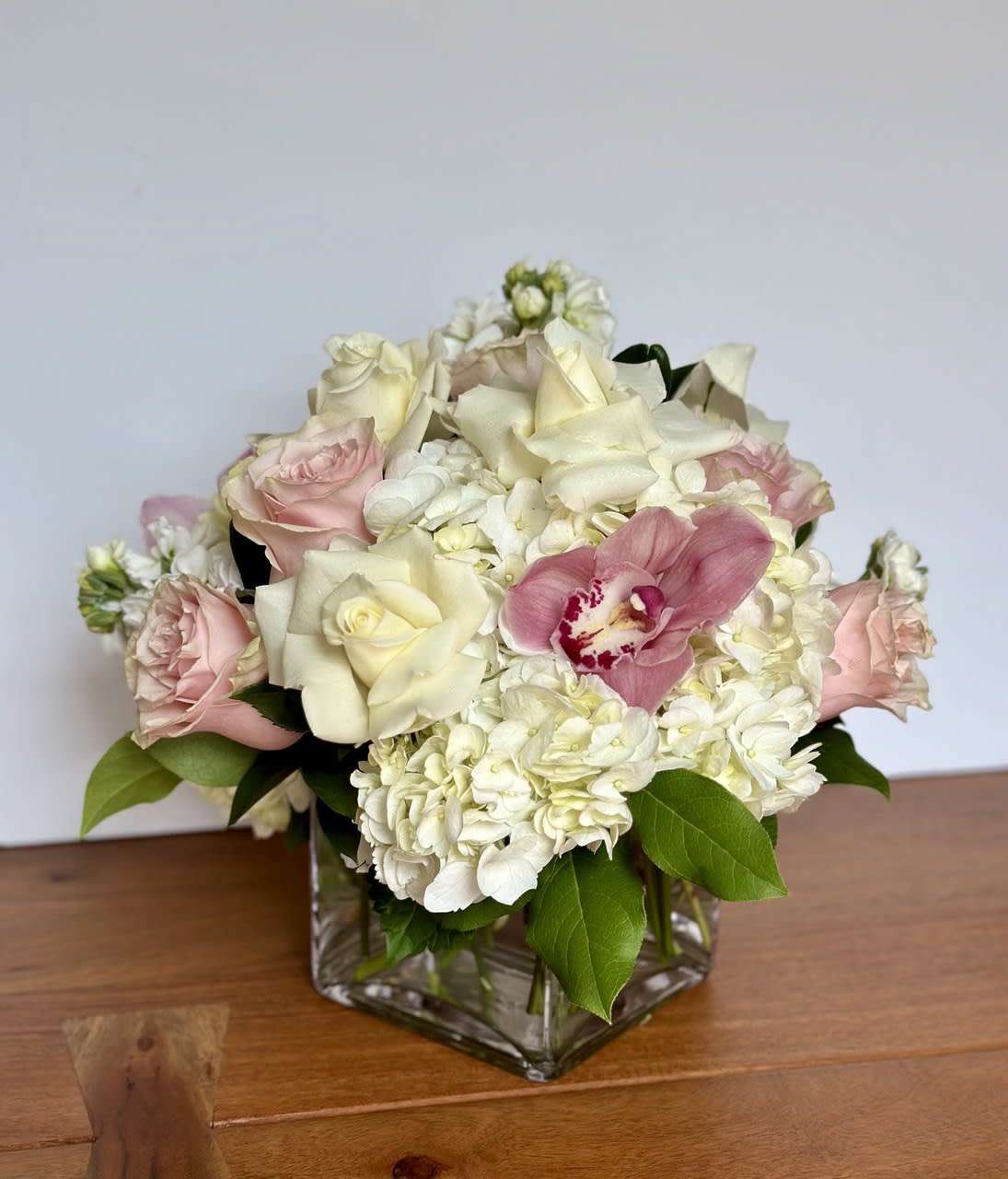 Pink and white roses with hydrangeas in a square glass vase