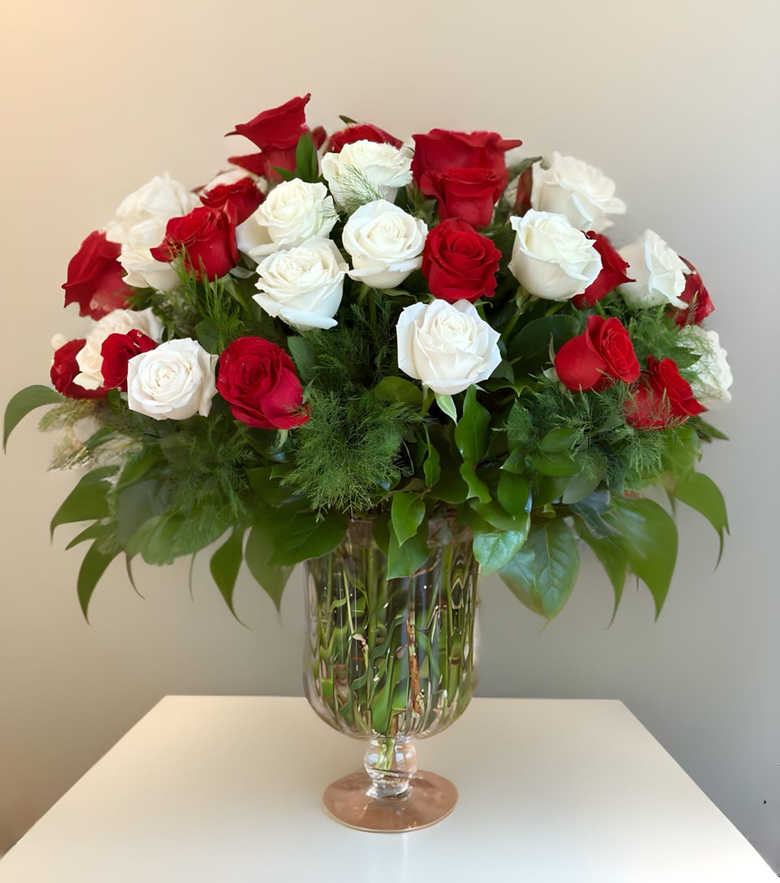 Red and white roses arranged in a clear glass vase