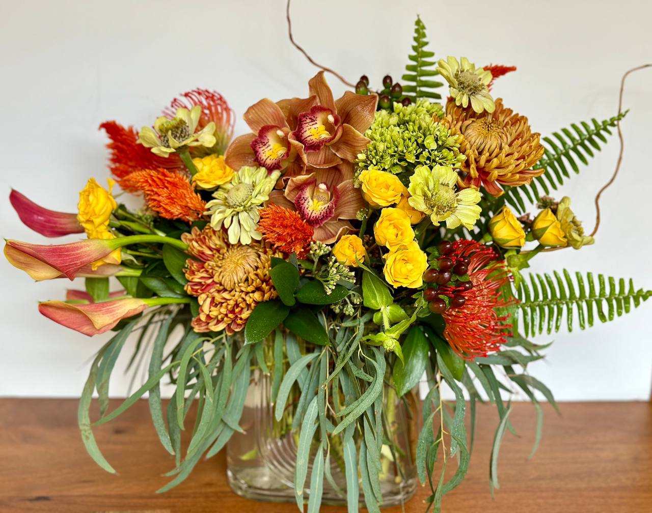 Mixed bouquet in a clear glass vase with yellow, orange, and pink blooms