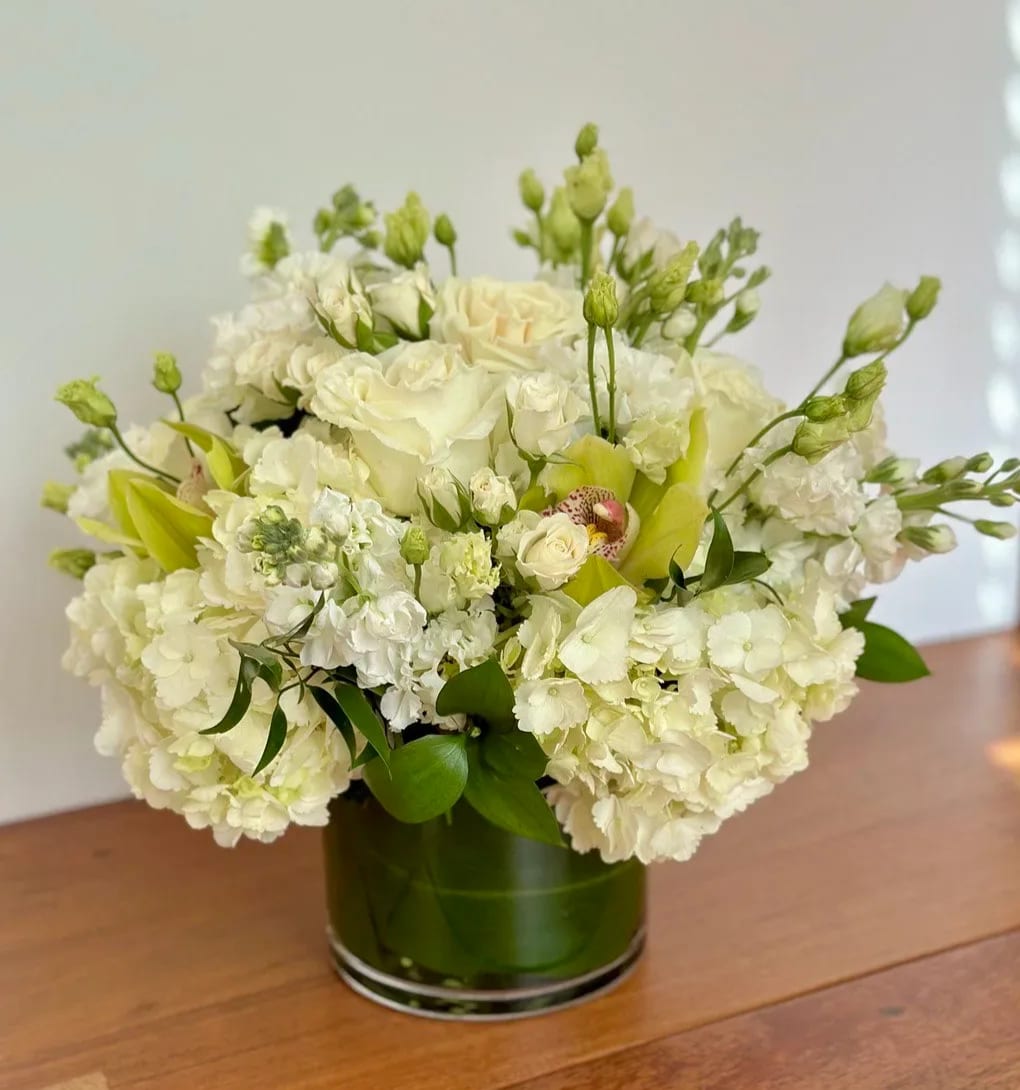 White floral arrangement in a green glass vase