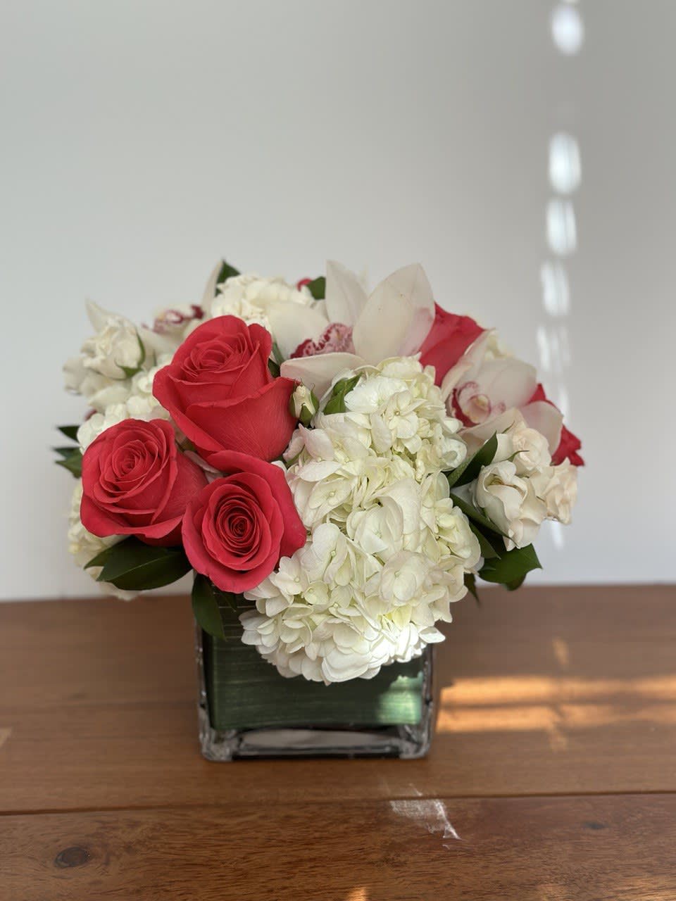 Red roses and white hydrangeas in a square glass vase