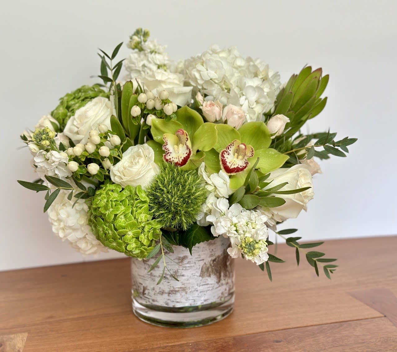 White and green floral arrangement in a glass vase