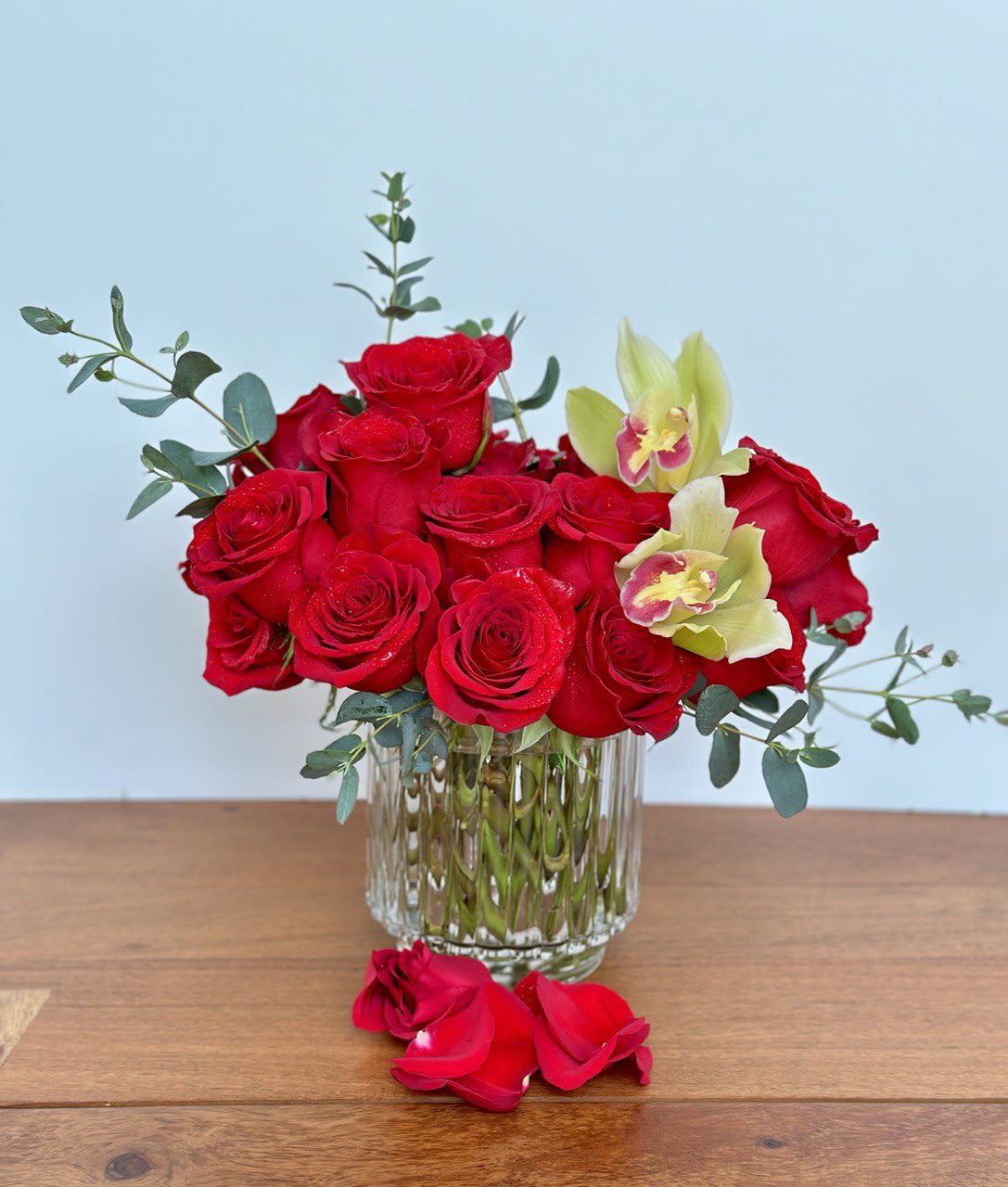 Red roses and pale orchids arranged in a clear glass vase