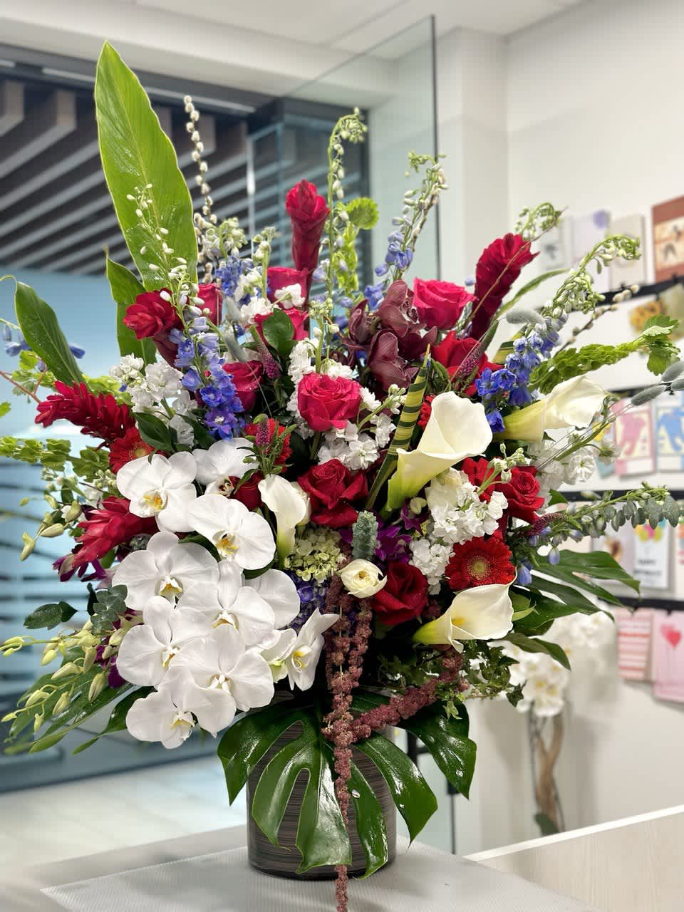 Large mixed bouquet with white orchids, red roses, and calla lilies in a vase