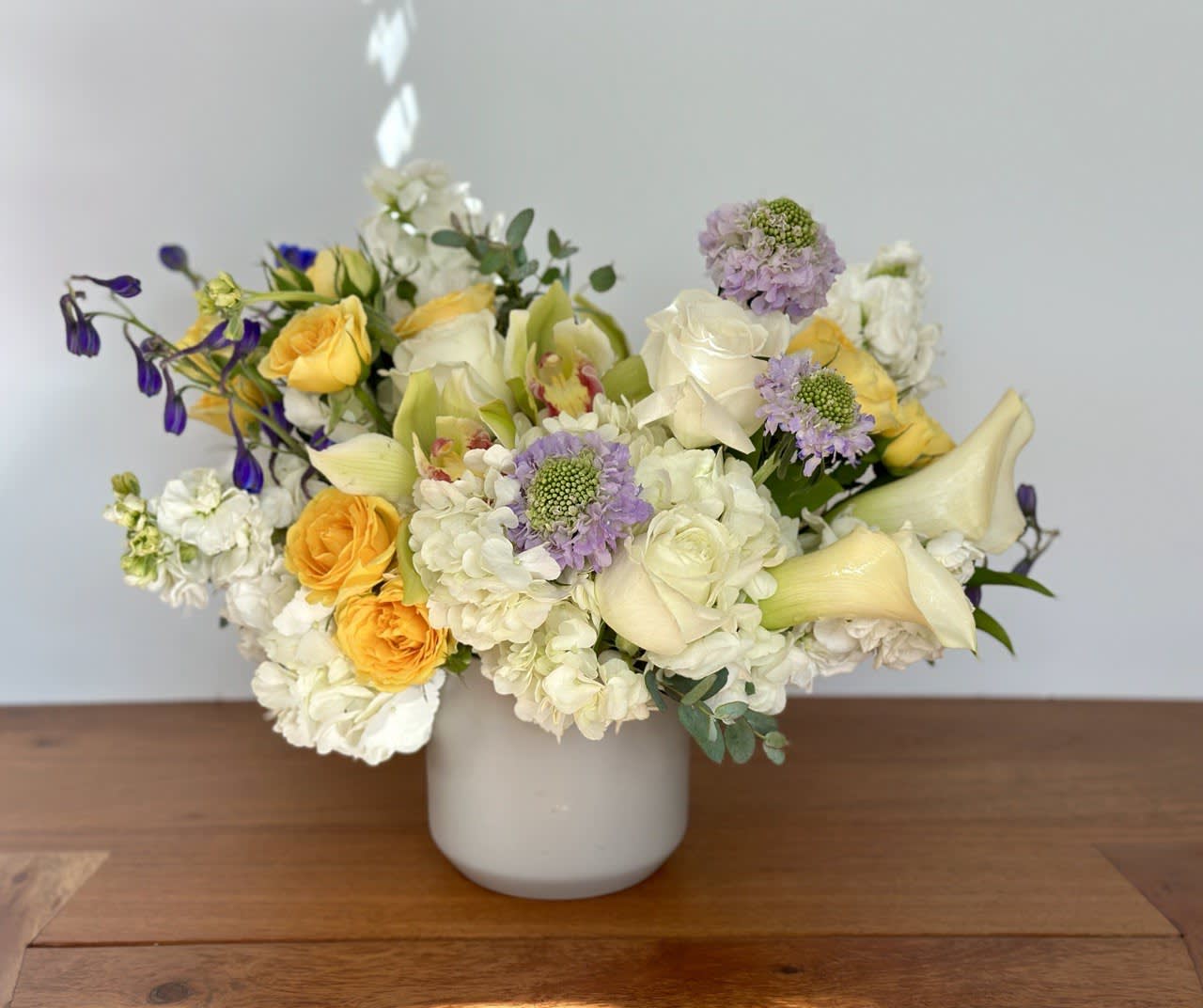 Mixed bouquet of white, yellow, and lavender flowers in a white vase