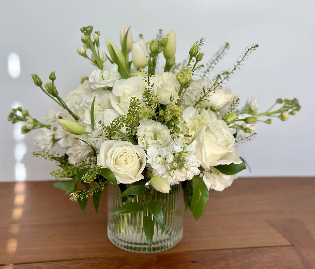 White roses and mixed white flowers in a clear glass vase