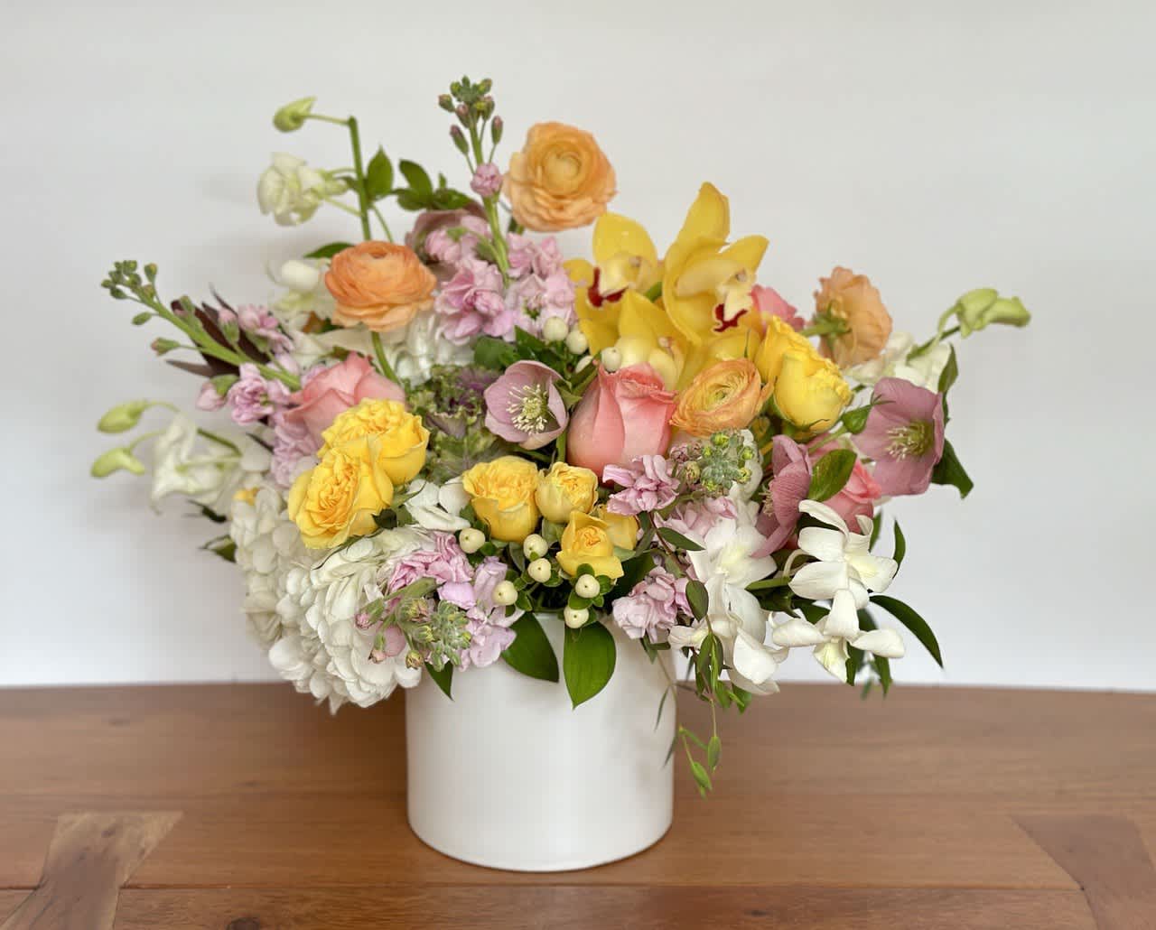 Mixed bouquet of yellow, pink, and white flowers in a white vase