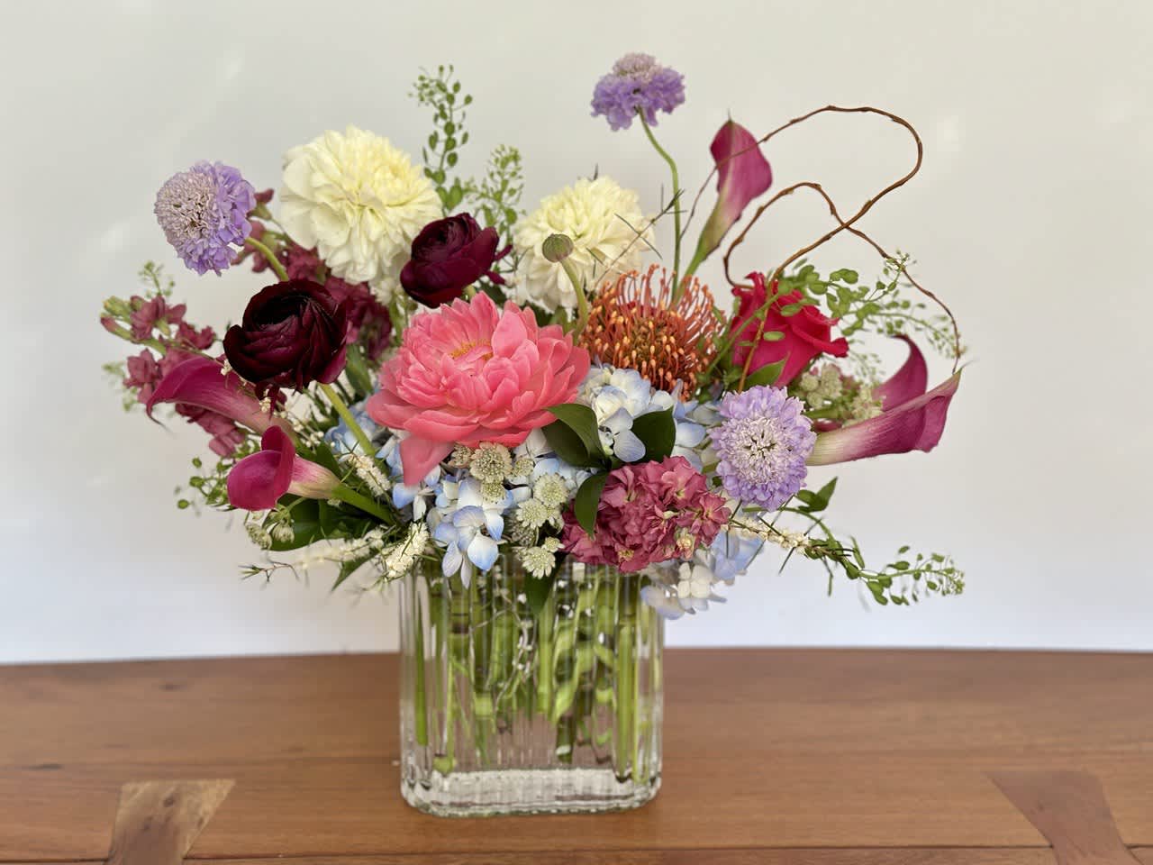 Mixed bouquet in a clear glass vase with pink, purple, white, and blue flowers