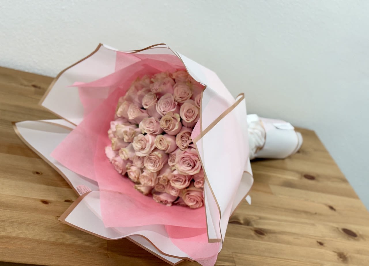 Bouquet of pale pink roses wrapped in white and pink paper