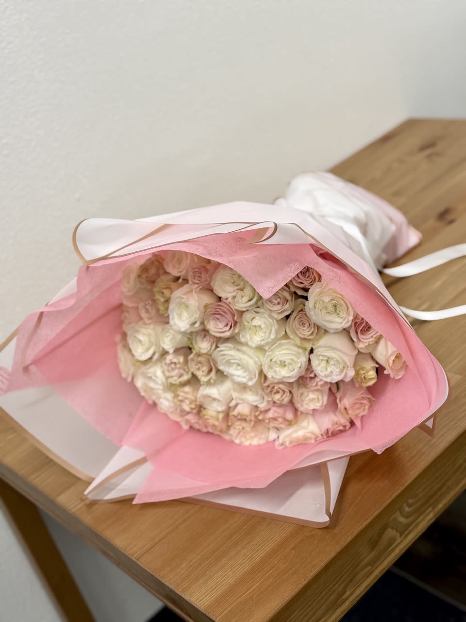 Bouquet of pale pink and white roses wrapped in pink paper