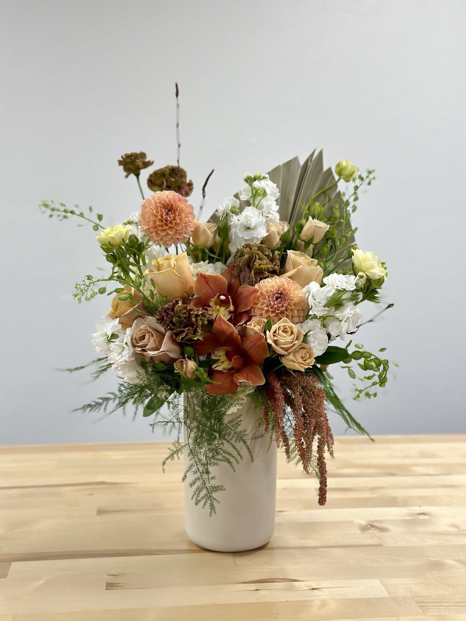 Peach and white floral arrangement in a white vase