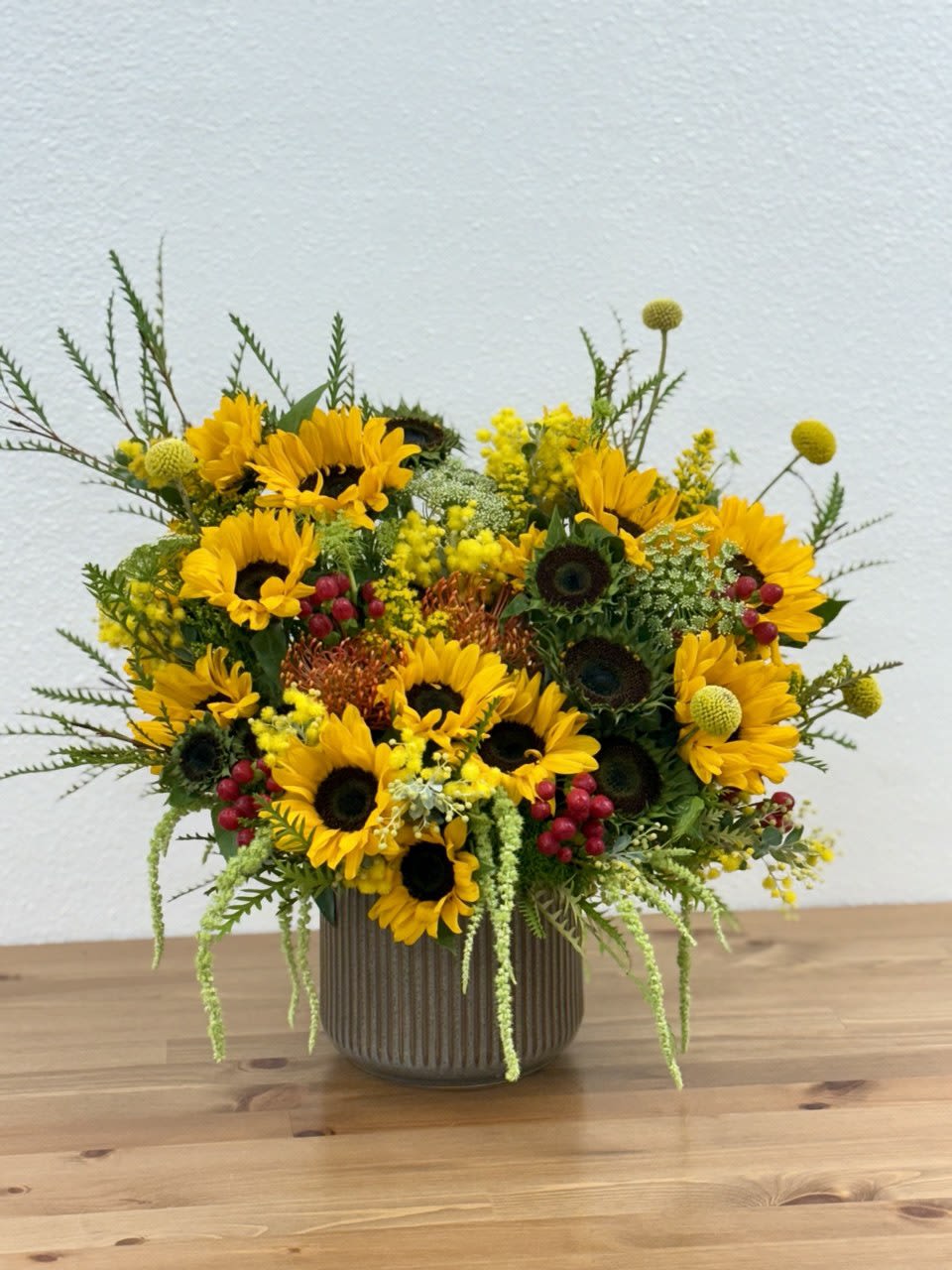 Sunflower arrangement in a ribbed vase with yellow and red accents