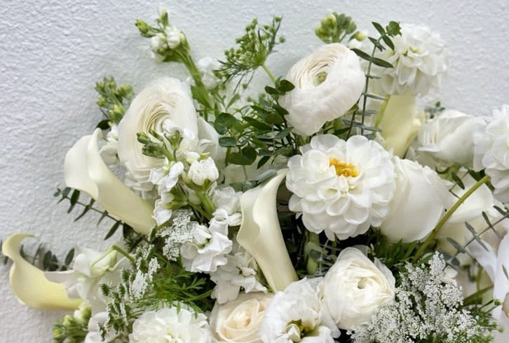 White floral arrangement with calla lilies, ranunculus, and dahlias