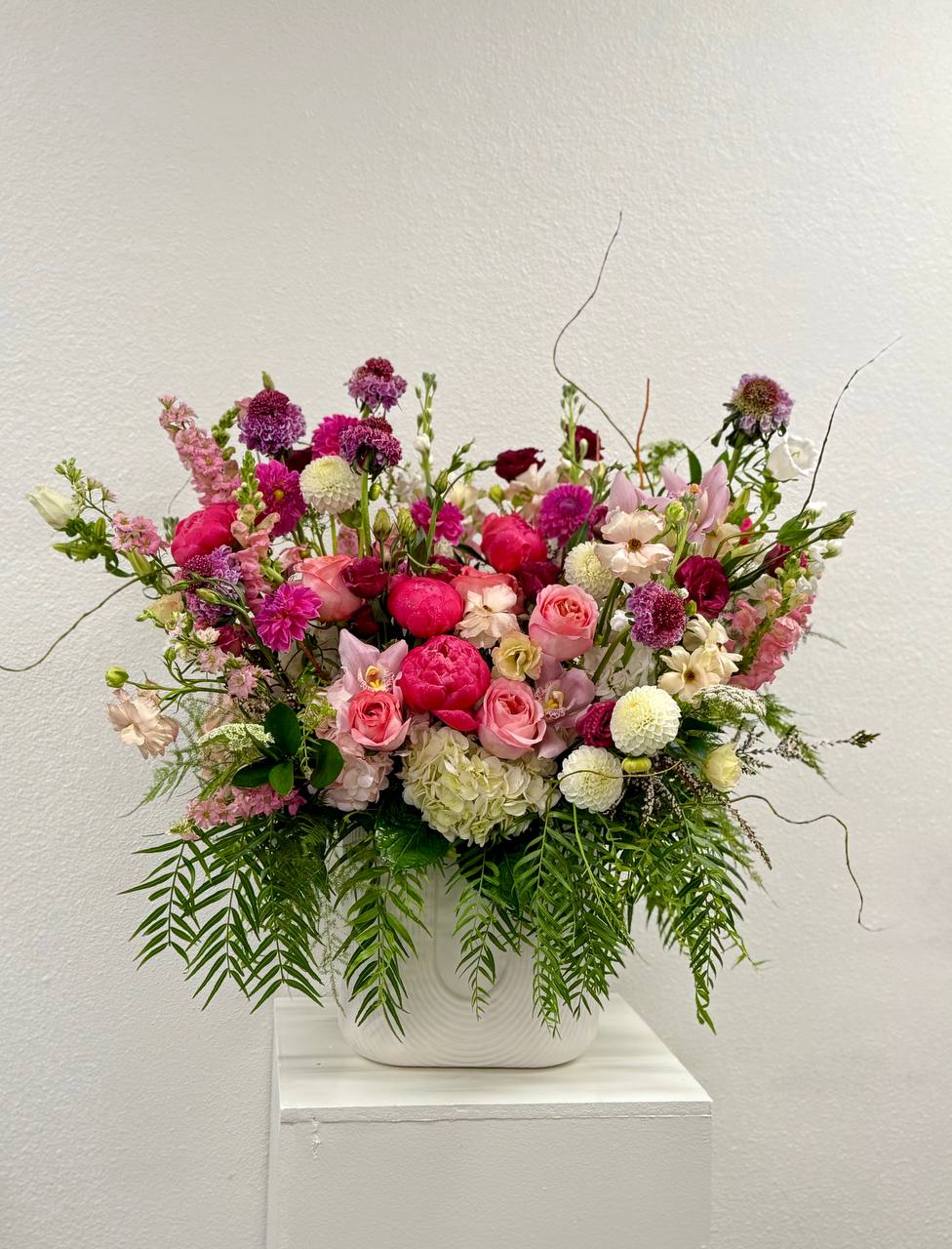 Large arrangement of pink and white mixed flowers in a white ceramic vase