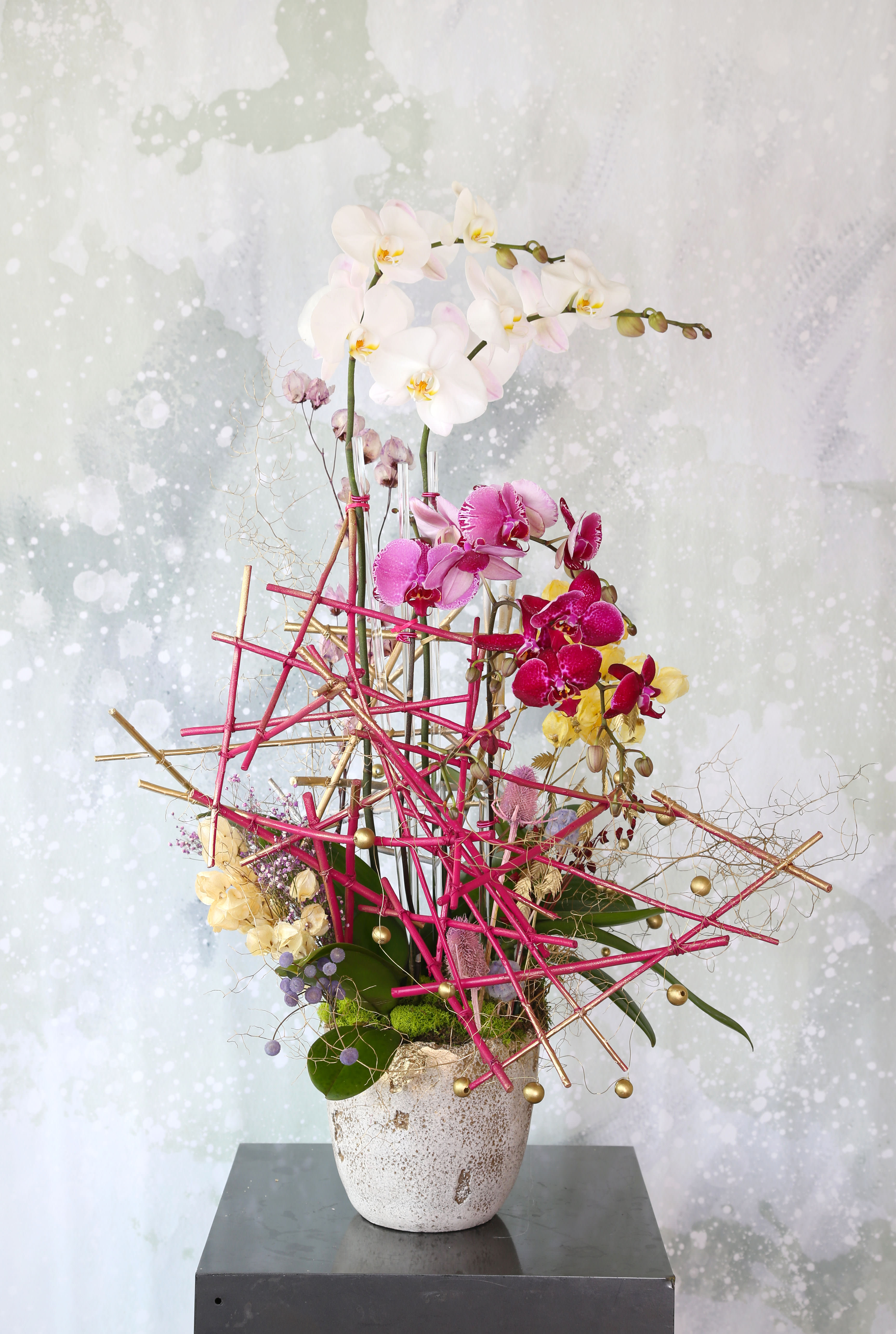 Scupture Orchid - This limited mother's day artful Orchid arrangement featuring large white Phalaenopsis orchids blooming and complemented with different shade magenta color Phalaenopise. Handmade wooden stick sculpture with all preserve material create a couture and one of a kind craftsmanship A perfect gift for mom to thankful for her warmth and kindness of heart . This arrangement about 40" height and 23" width and depth.