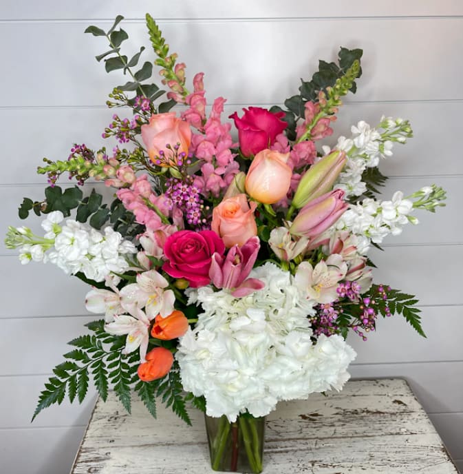 Tall pink and white mixed flower arrangement with roses and lilies in a clear glass vase