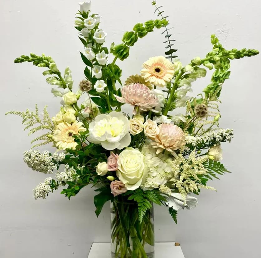 Tall mixed bouquet in a clear glass vase with white and pale pink flowers