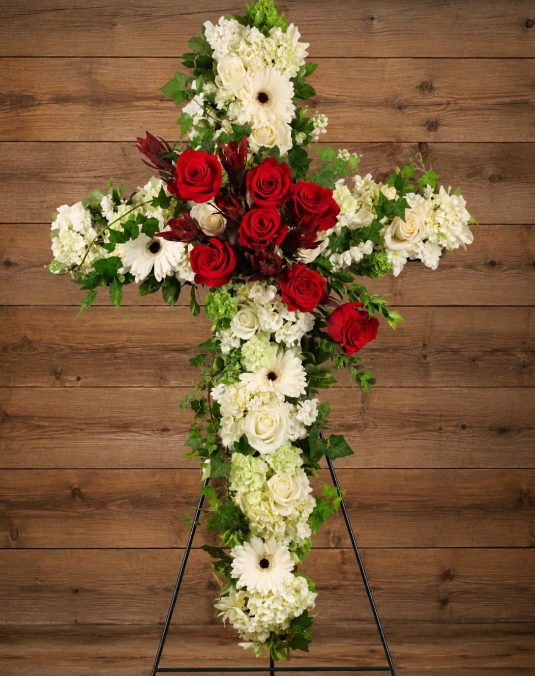 Cross-shaped floral arrangement with red and white flowers on a stand