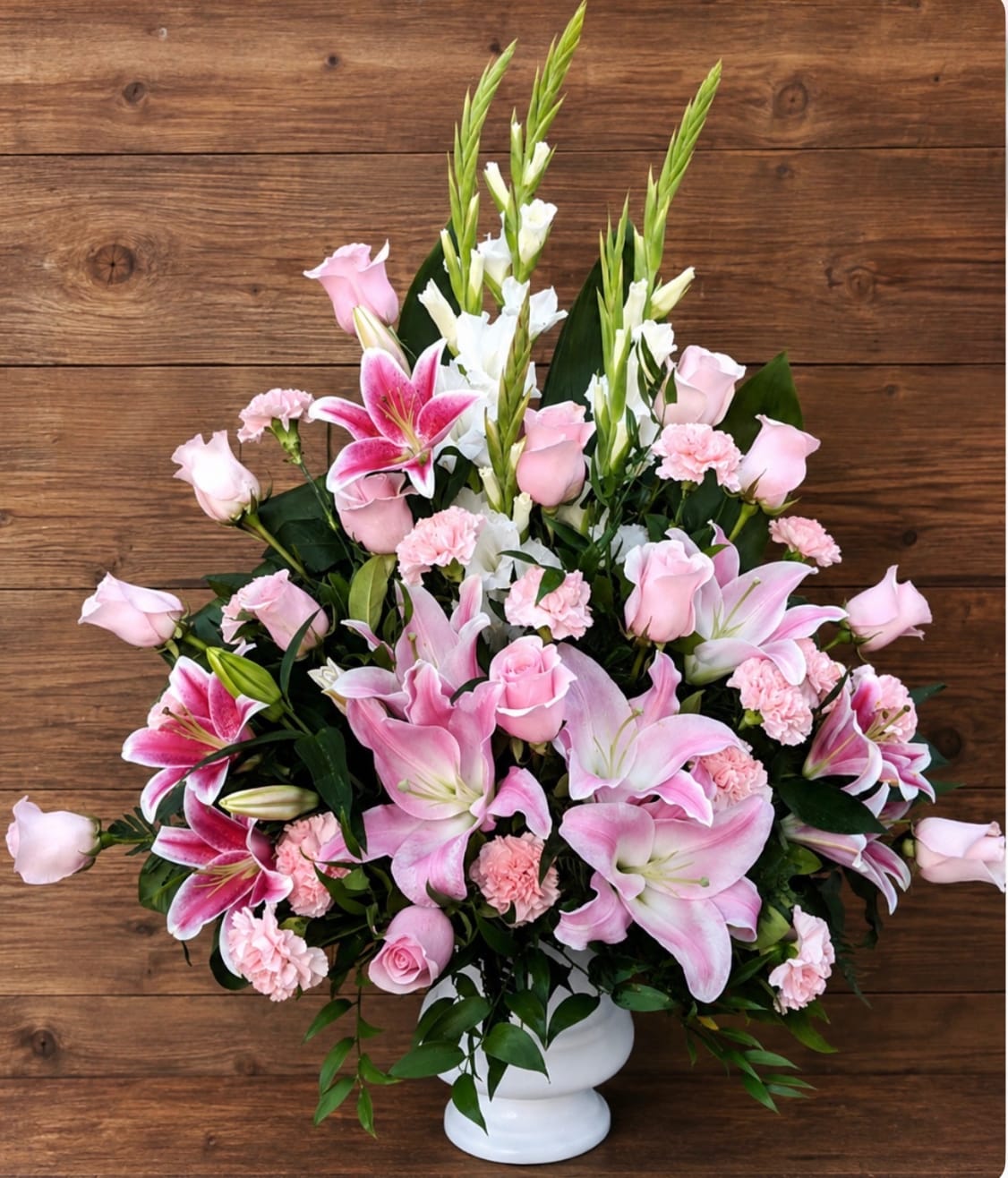 Pink lilies and roses arranged in a white vase