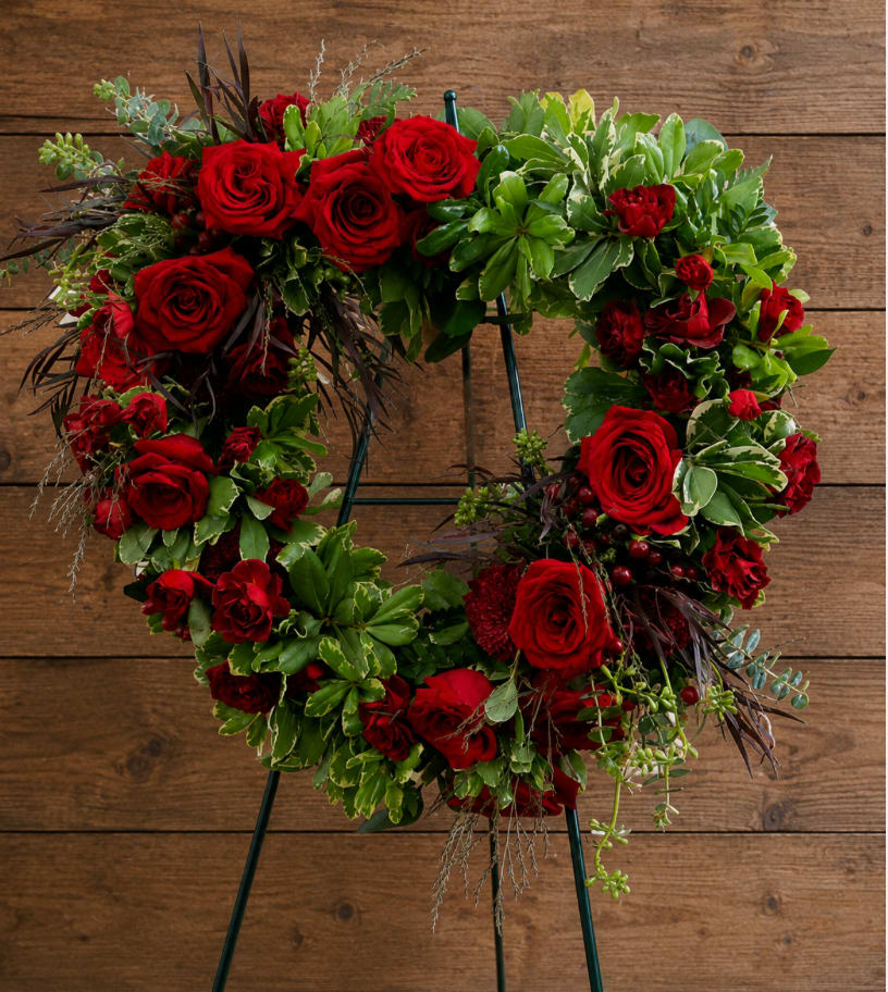 Heart-shaped wreath of red roses and greenery on a stand
