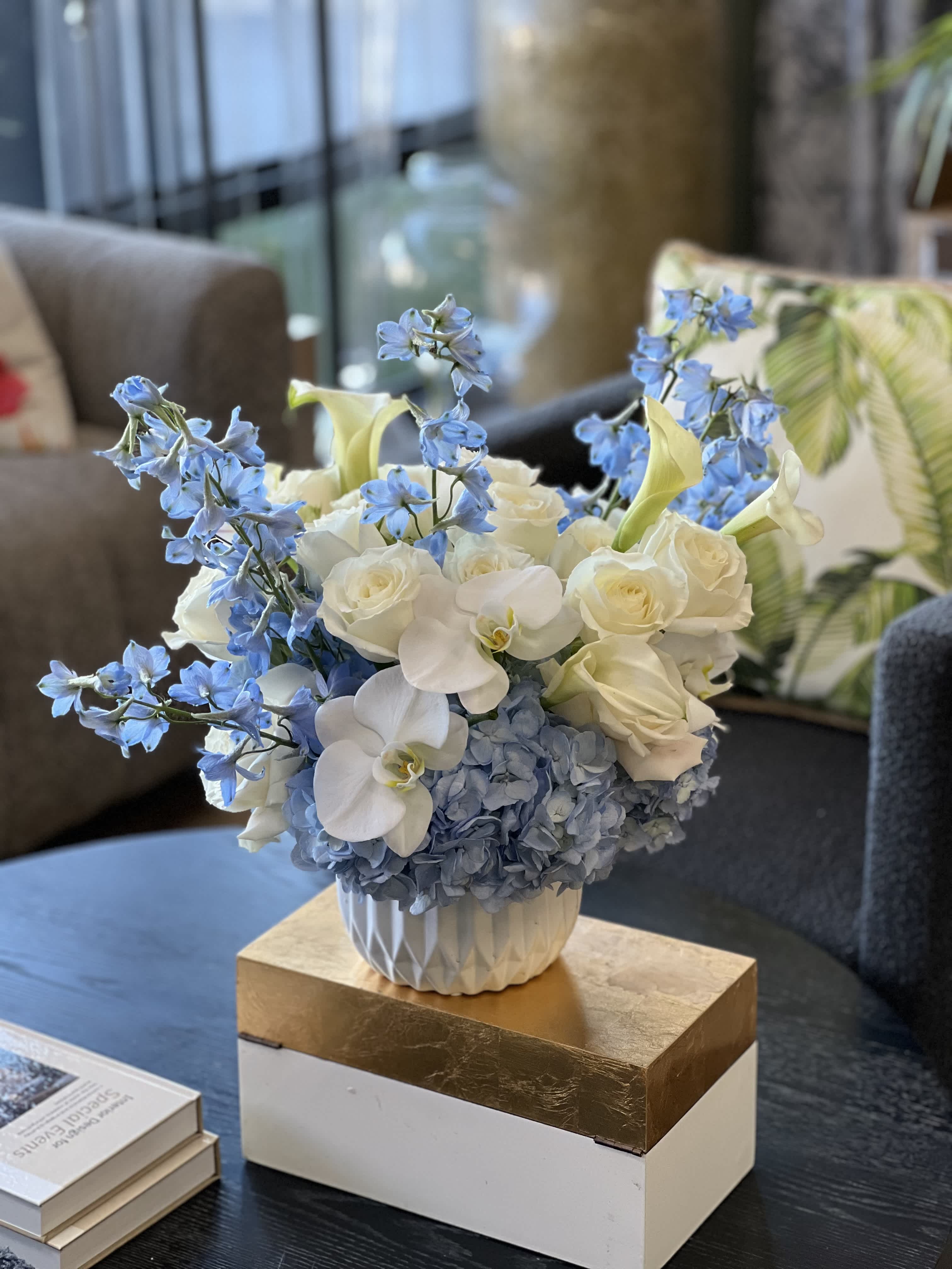 Blue and white floral arrangement in a white vase on a table