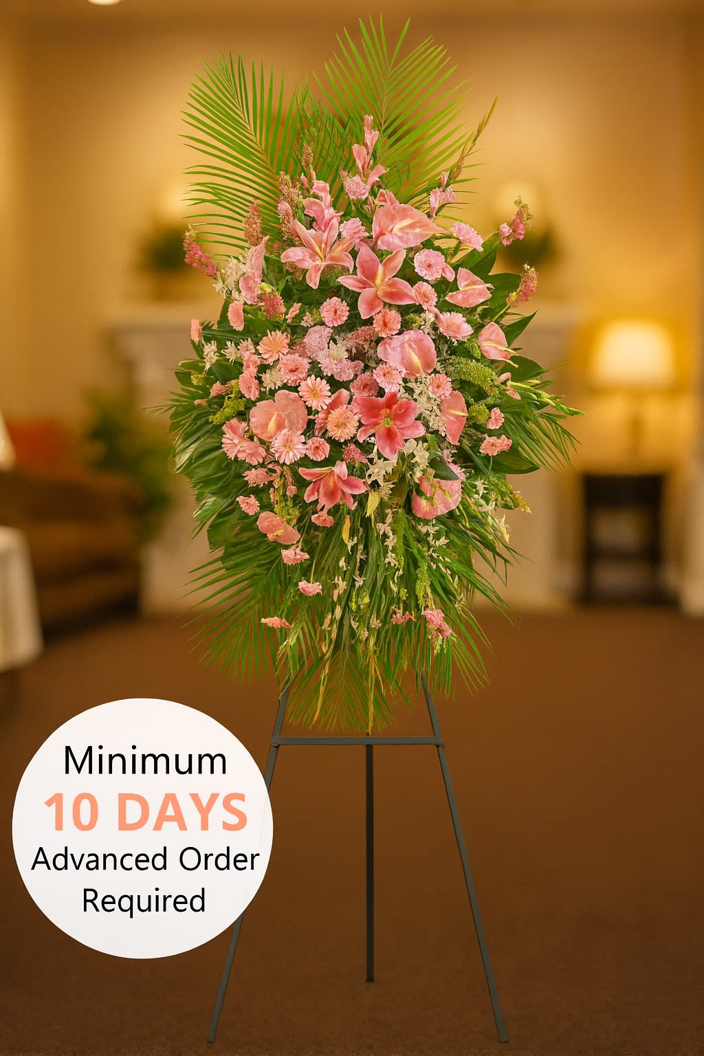 Tall pink standing spray of lilies and carnations with palm leaves on a black easel