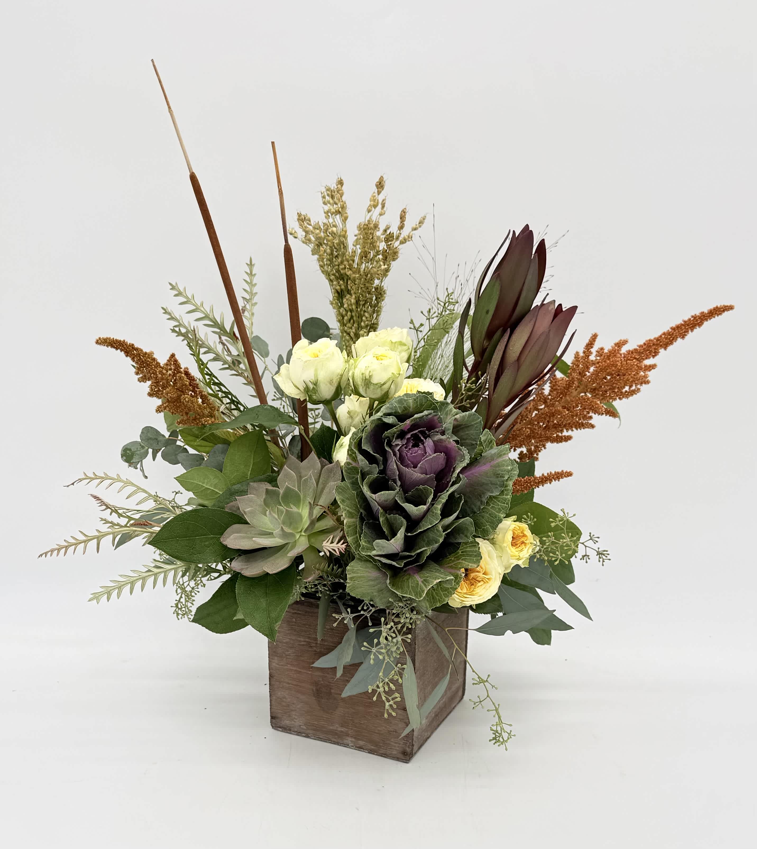 Mixed floral arrangement in a wooden box with purple and cream blooms