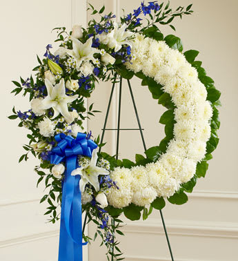 White floral wreath with blue ribbon on a stand