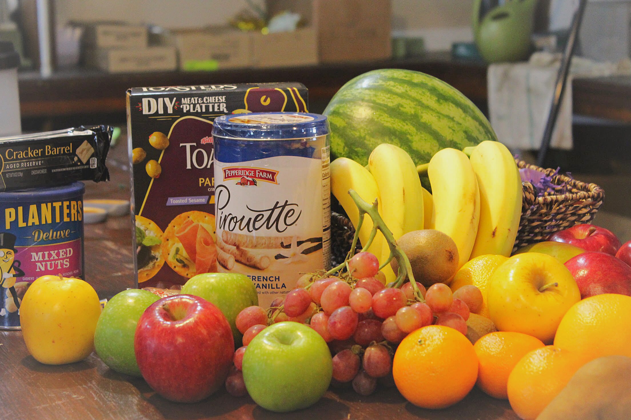 Assorted fruit and snack gift basket with bananas, apples, grapes, and packaged treats