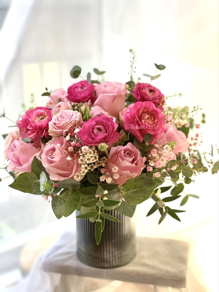 Pink roses and ranunculus in a ribbed vase
